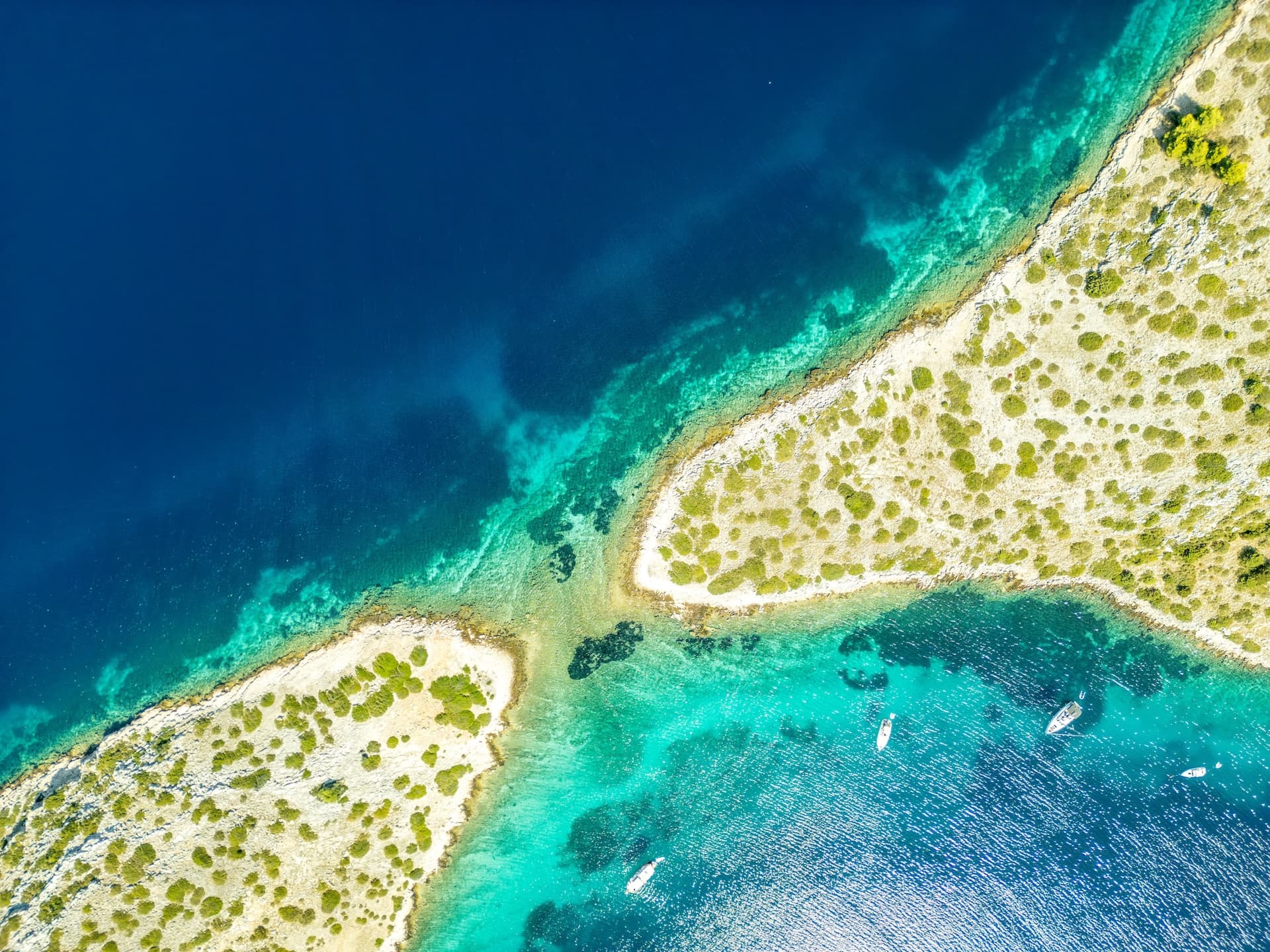 Aerial view of arid islands and turquoise water with boats anchored near Kornati Bay.