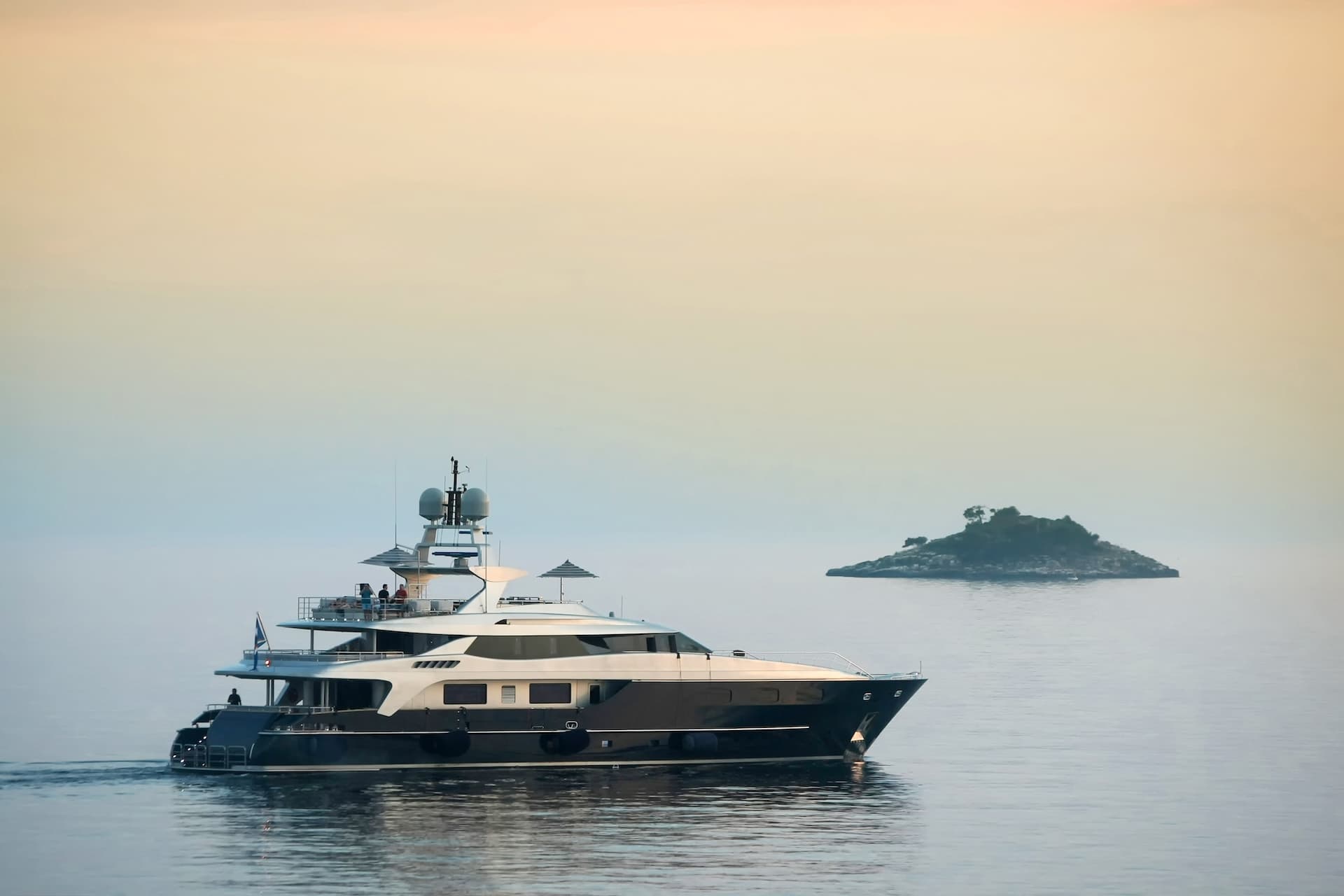 Luxury yacht cruising near a small, tree-covered island in calm coastal waters, Croatia.