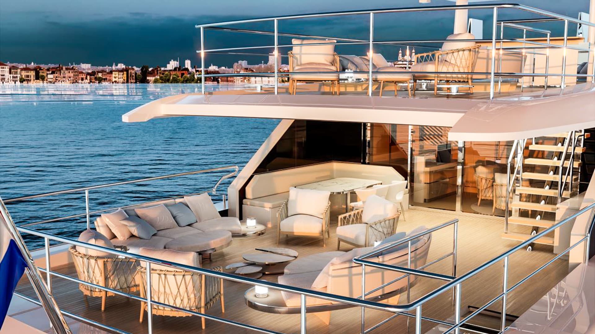 Aft deck of a luxury yacht with outdoor lounge seating overlooking a distant city skyline.