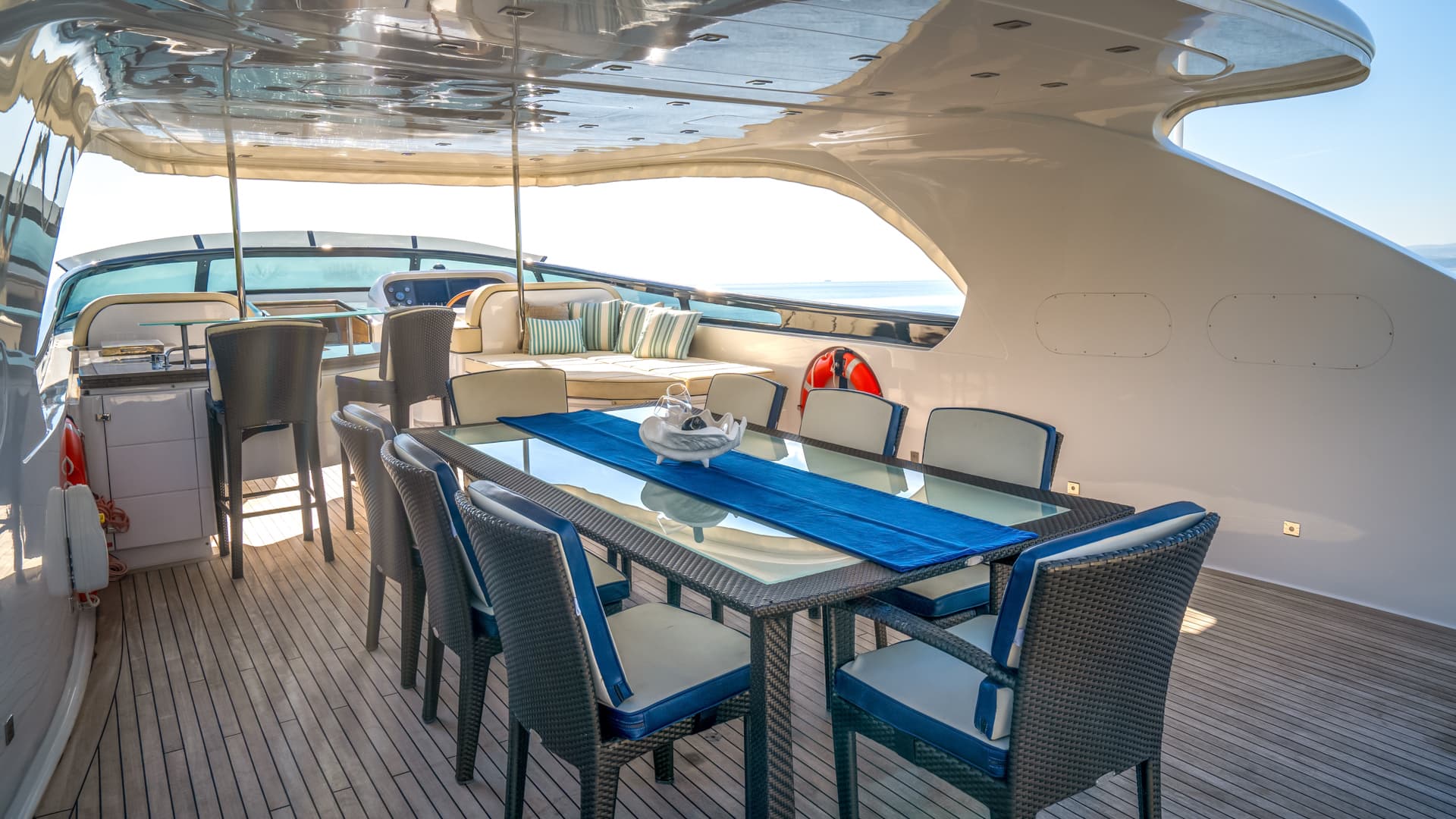 Flybridge dining table with wicker chairs on a yacht deck overlooking the sea