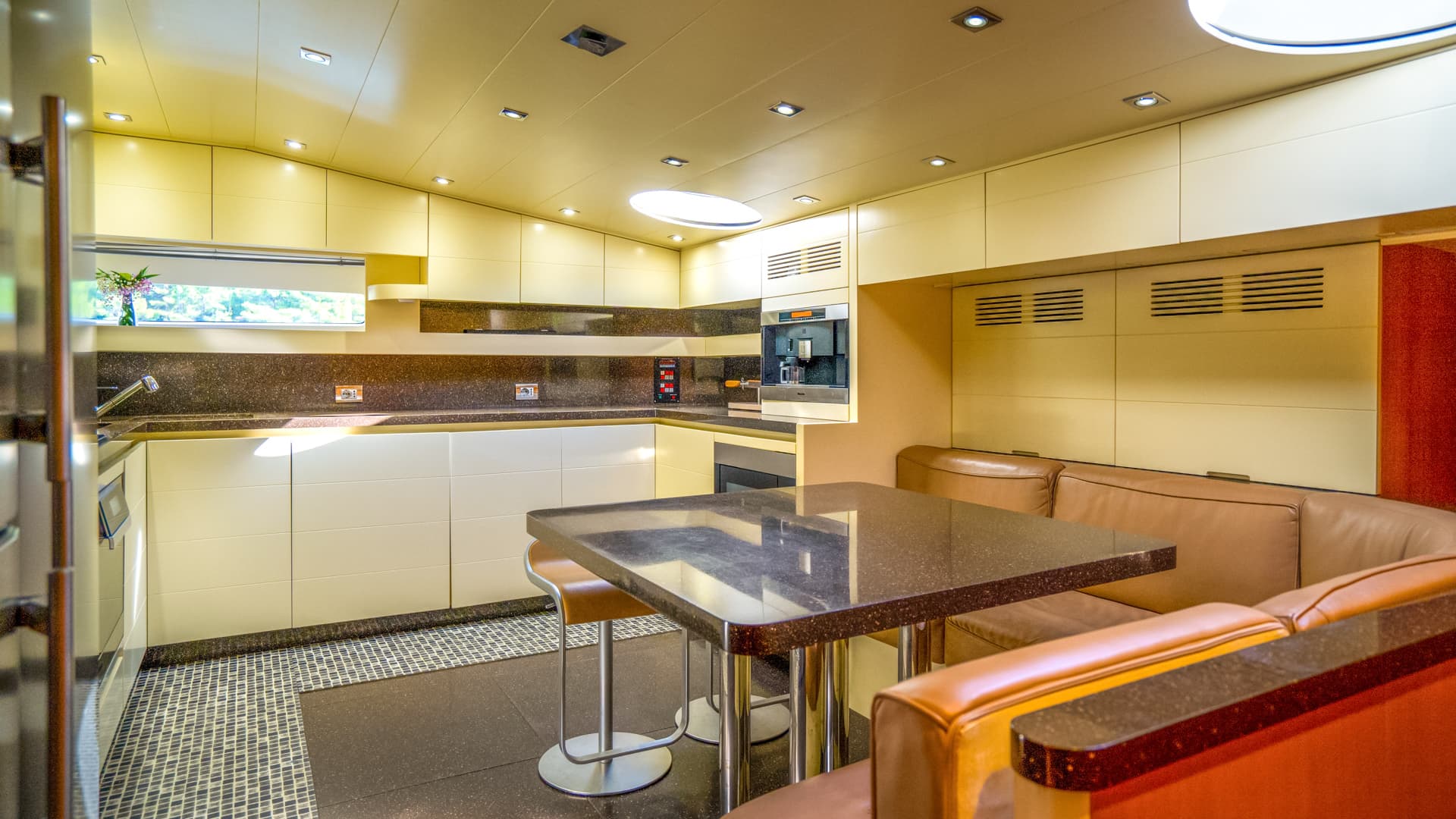 Compact galley kitchen with cream cabinets, dark counters, and built-in dining booth.