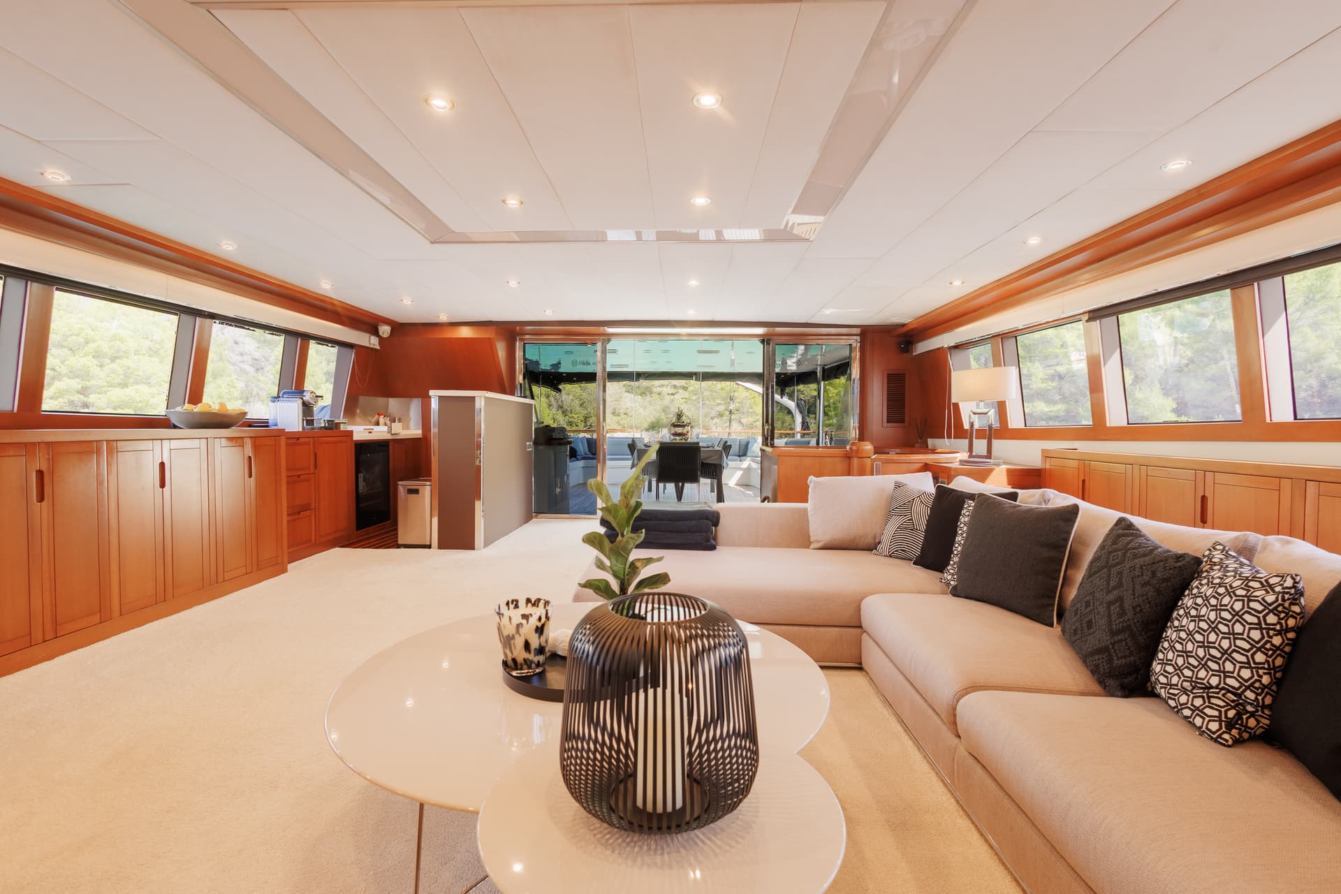 Yacht salon interior with light sofa, wood paneling, and view toward aft deck.