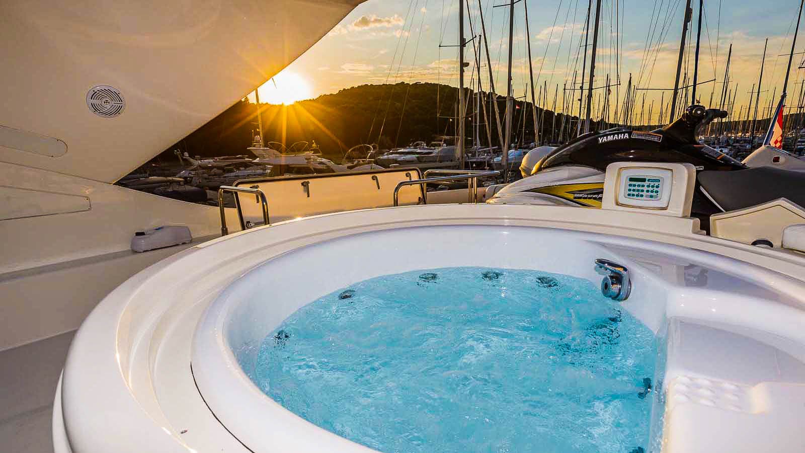 Jacuzzi bubbling on a yacht deck overlooking a marina at sunset