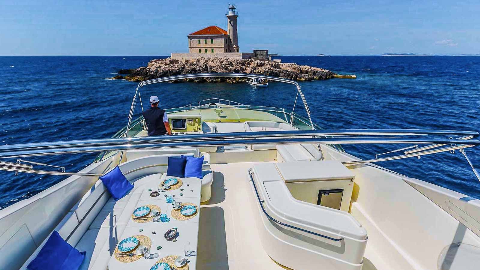 View from yacht flybridge toward lighthouse on rocky island in deep blue sea
