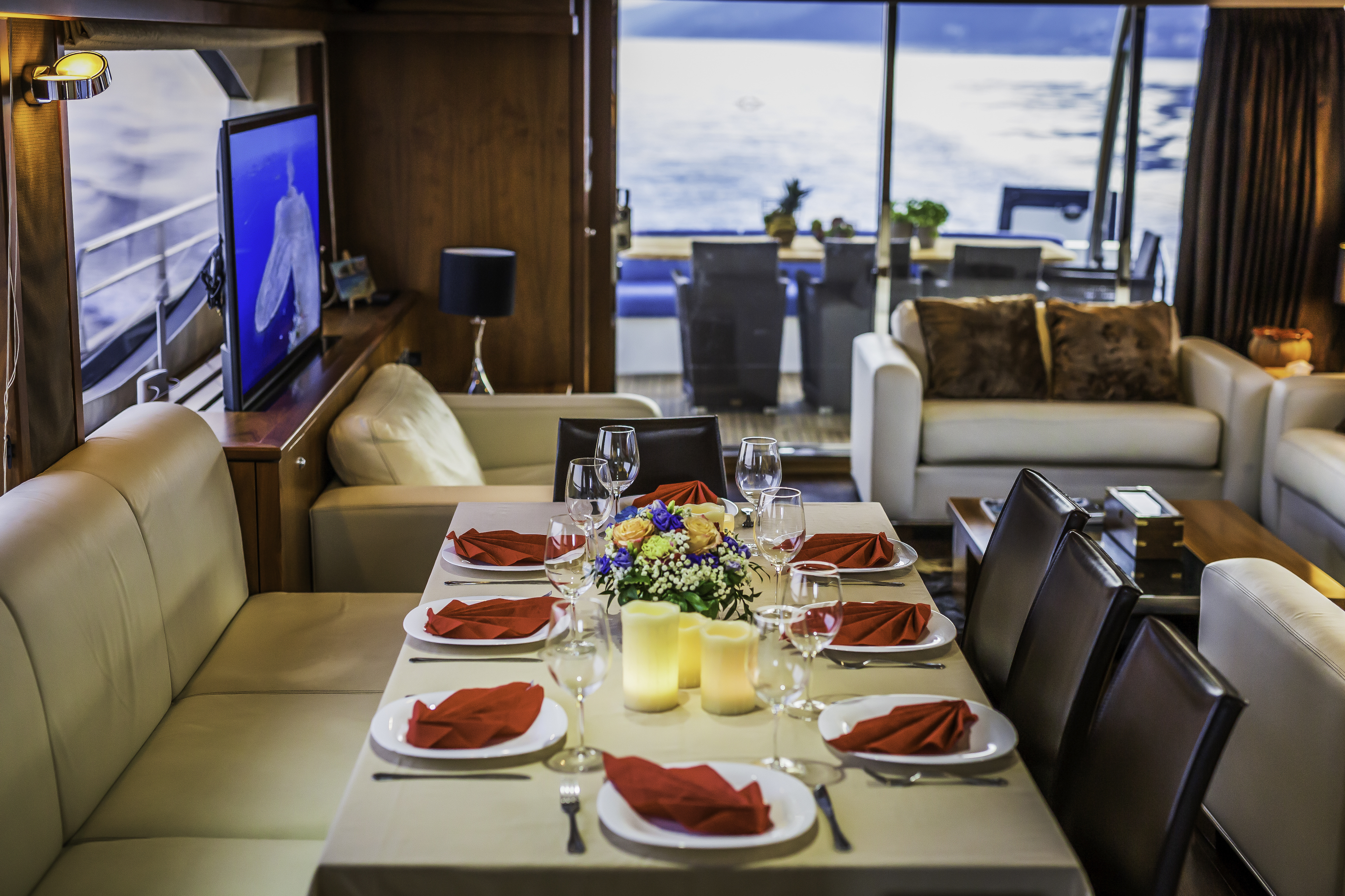 Dining table set for dinner inside a yacht cabin with ocean view