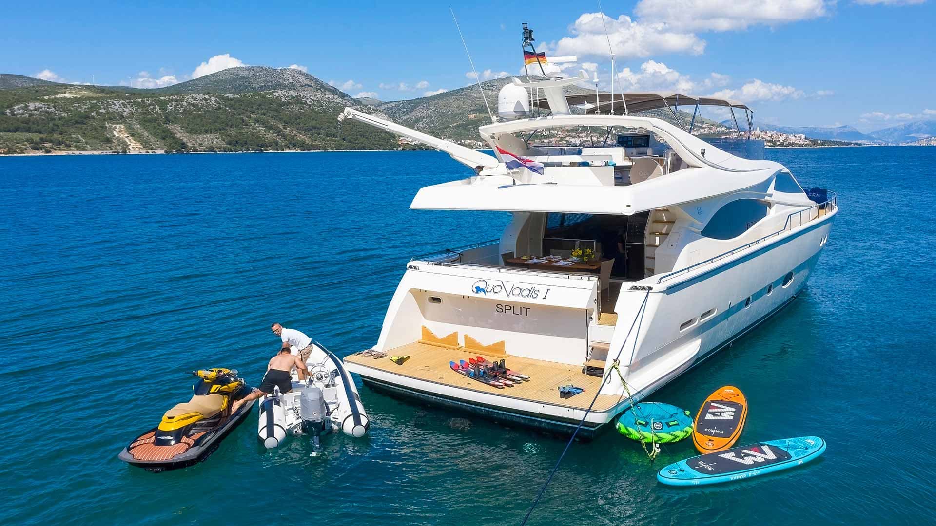 Luxury yacht "Quo Vadis I" from Split anchored in blue water with jet ski and water toys near mountains.