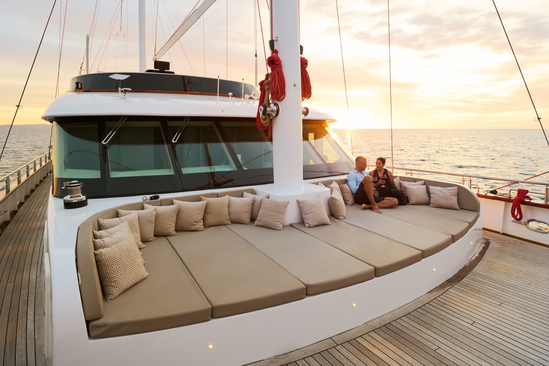 Couple relaxing on yacht deck with cushions at sunset over the ocean
