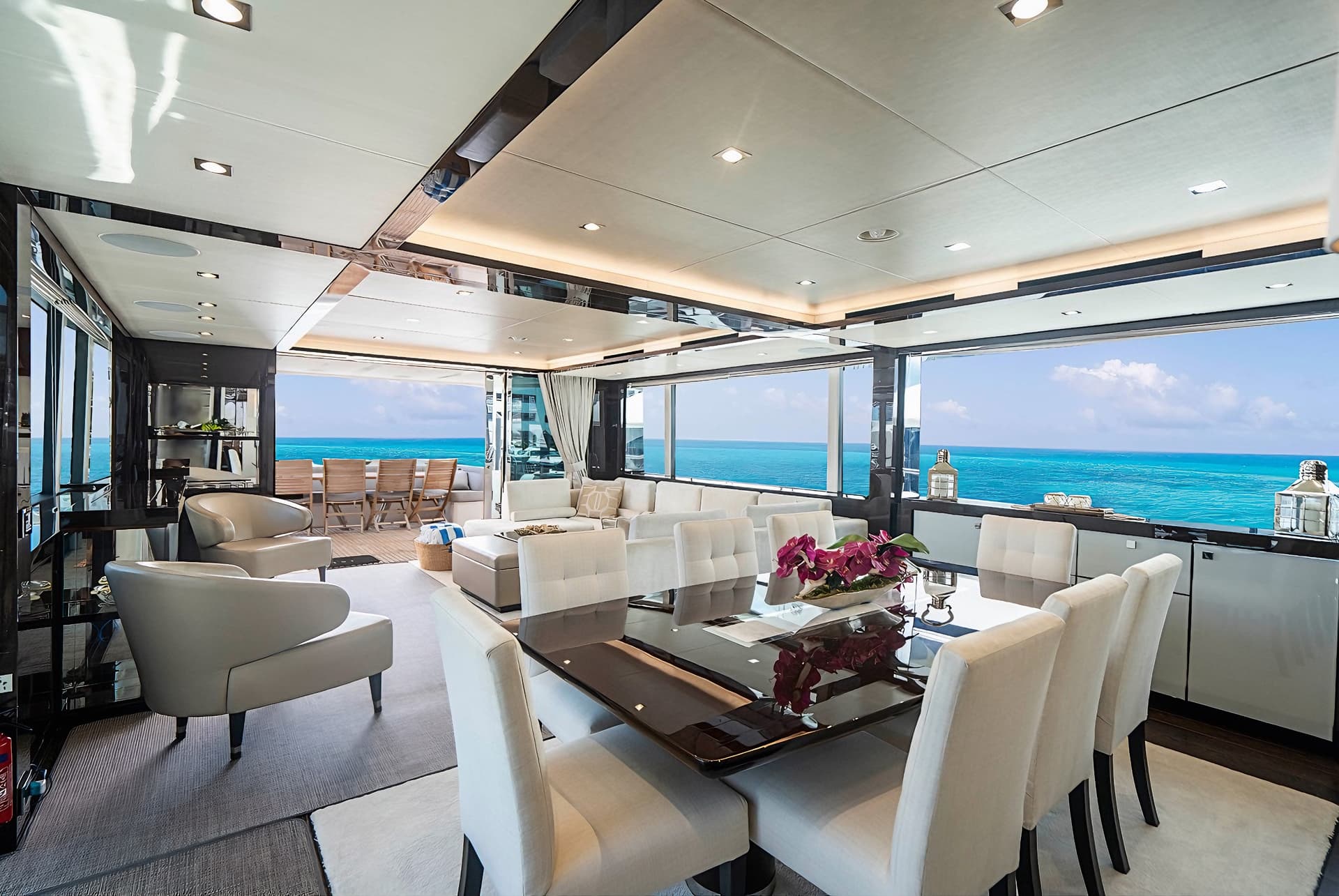Luxury yacht interior with dining area, lounge, and view of turquoise ocean water.