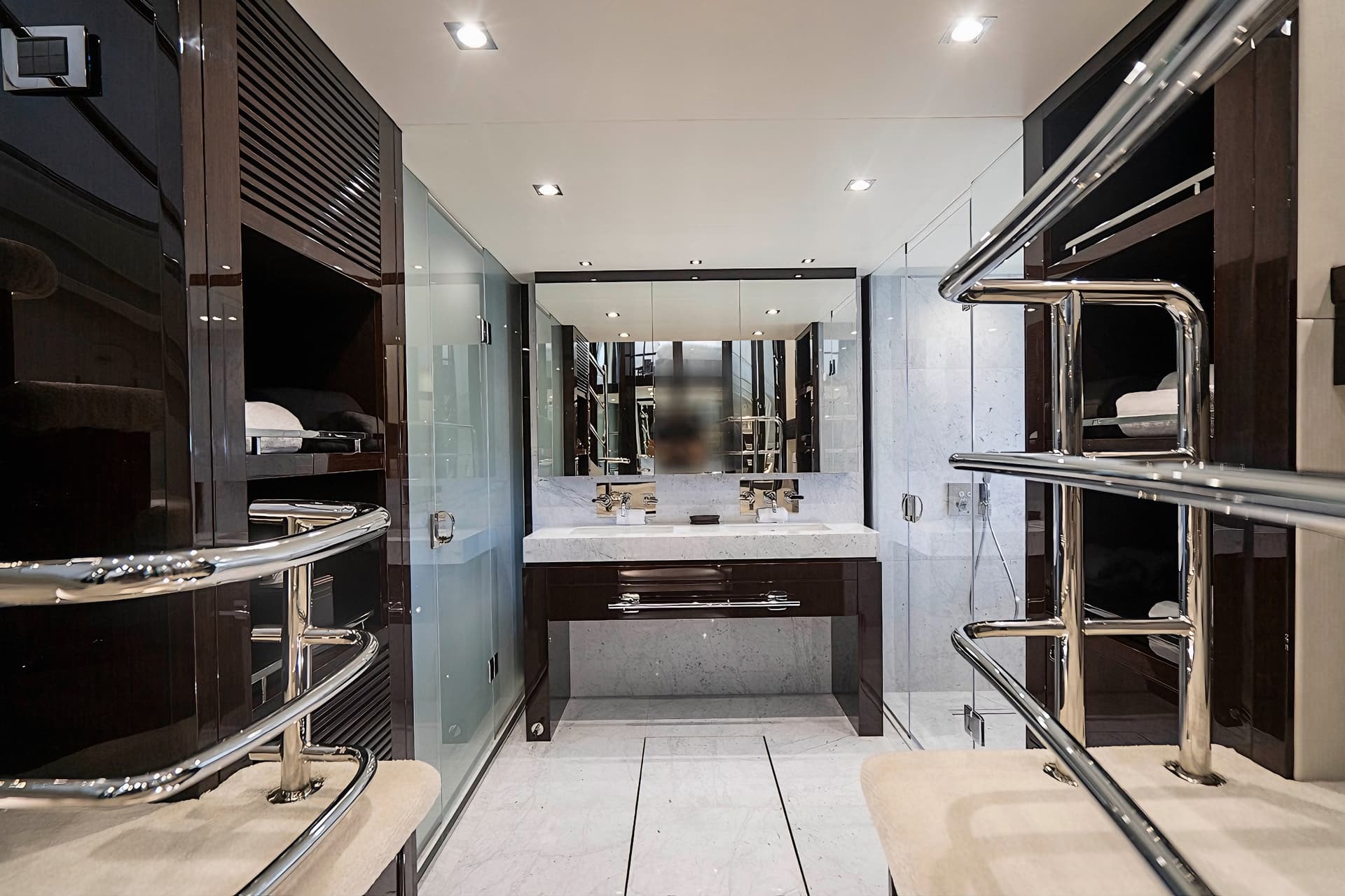 Luxury yacht bathroom with dual sinks, marble, dark wood, and chrome grab bars.