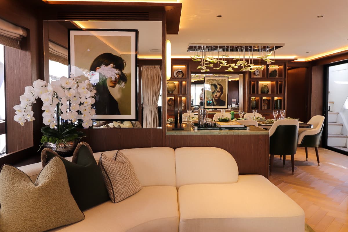 Luxury yacht main deck saloon with white orchids, modern art, and dining area.