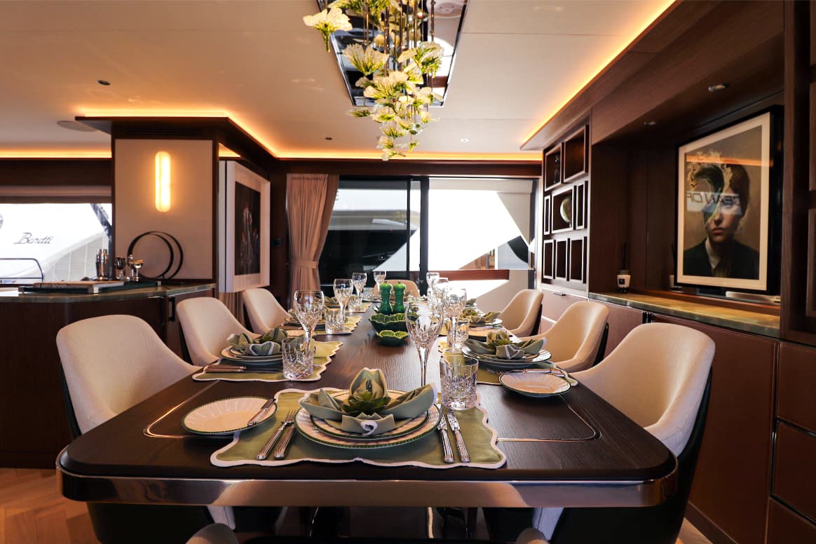Luxury yacht dining saloon set for a formal meal with elegant place settings and modern lighting.