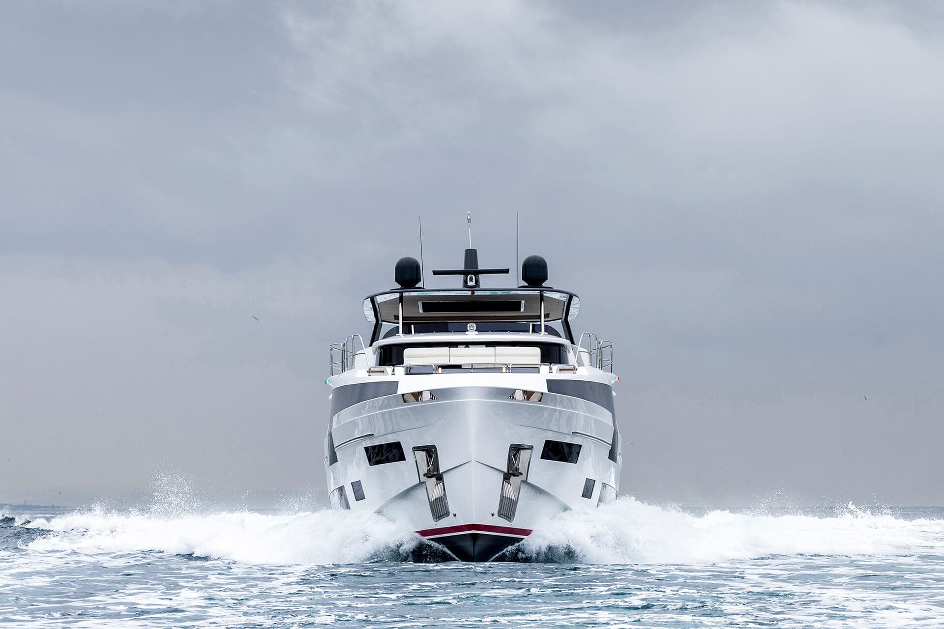 Motor yacht speeding through choppy water under a gray, overcast sky
