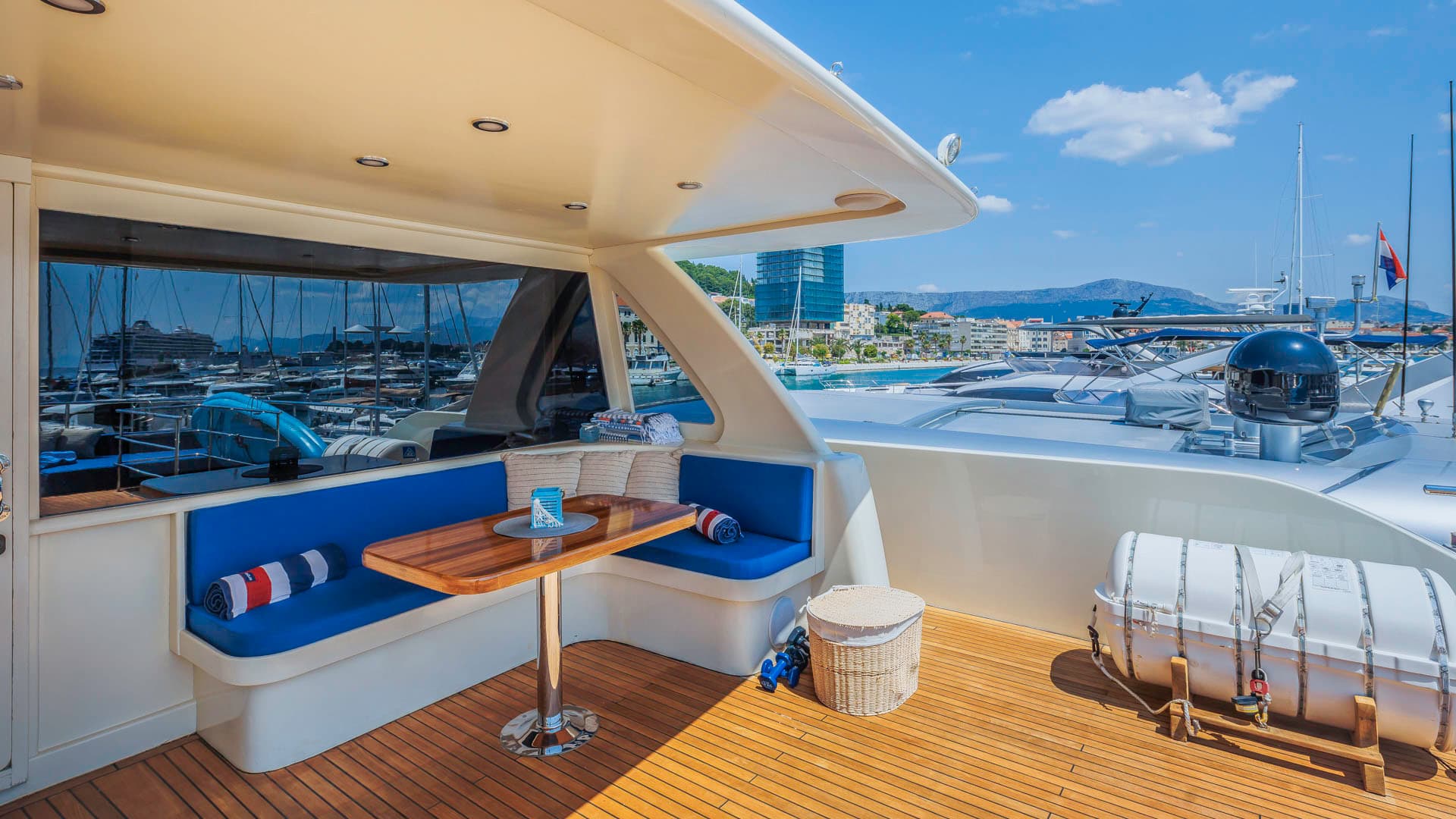Flybridge seating area with teak deck overlooking a busy harbor and coastal town.