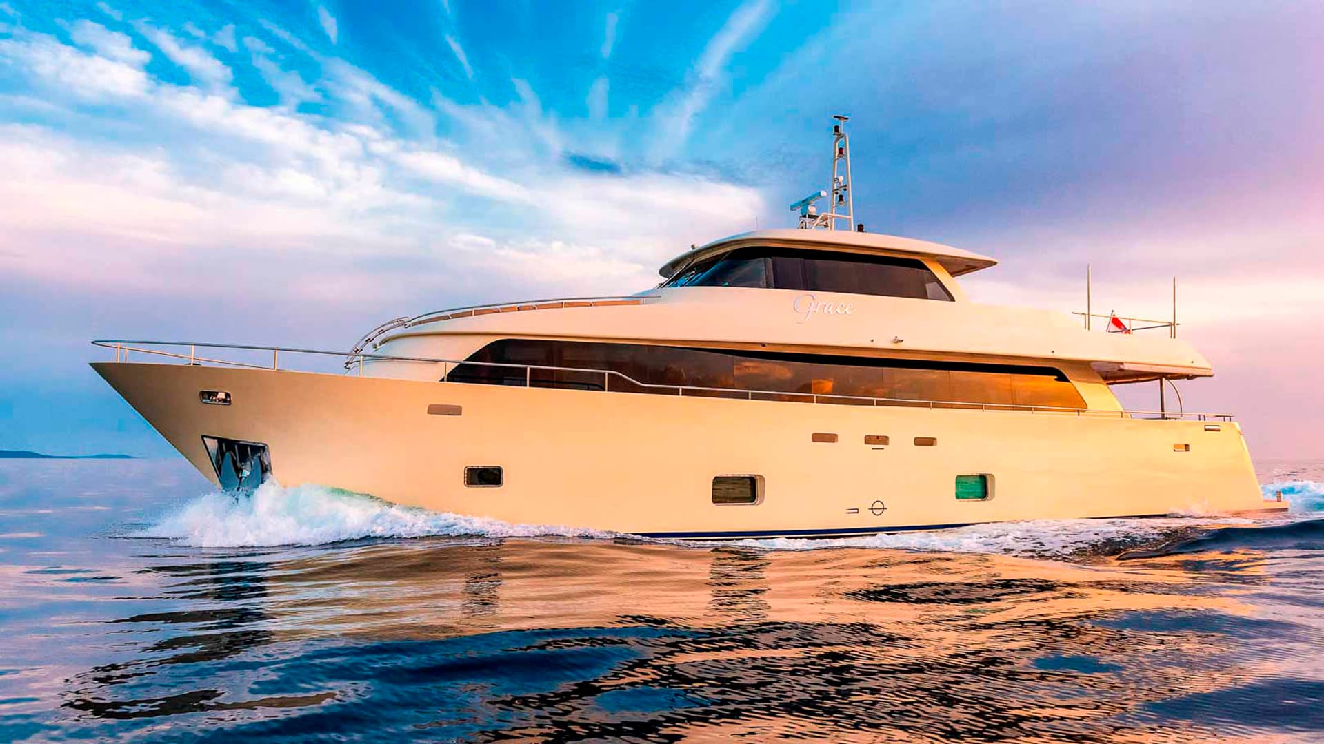 Motor yacht "Grace" cruising on blue water with colorful sunset reflections