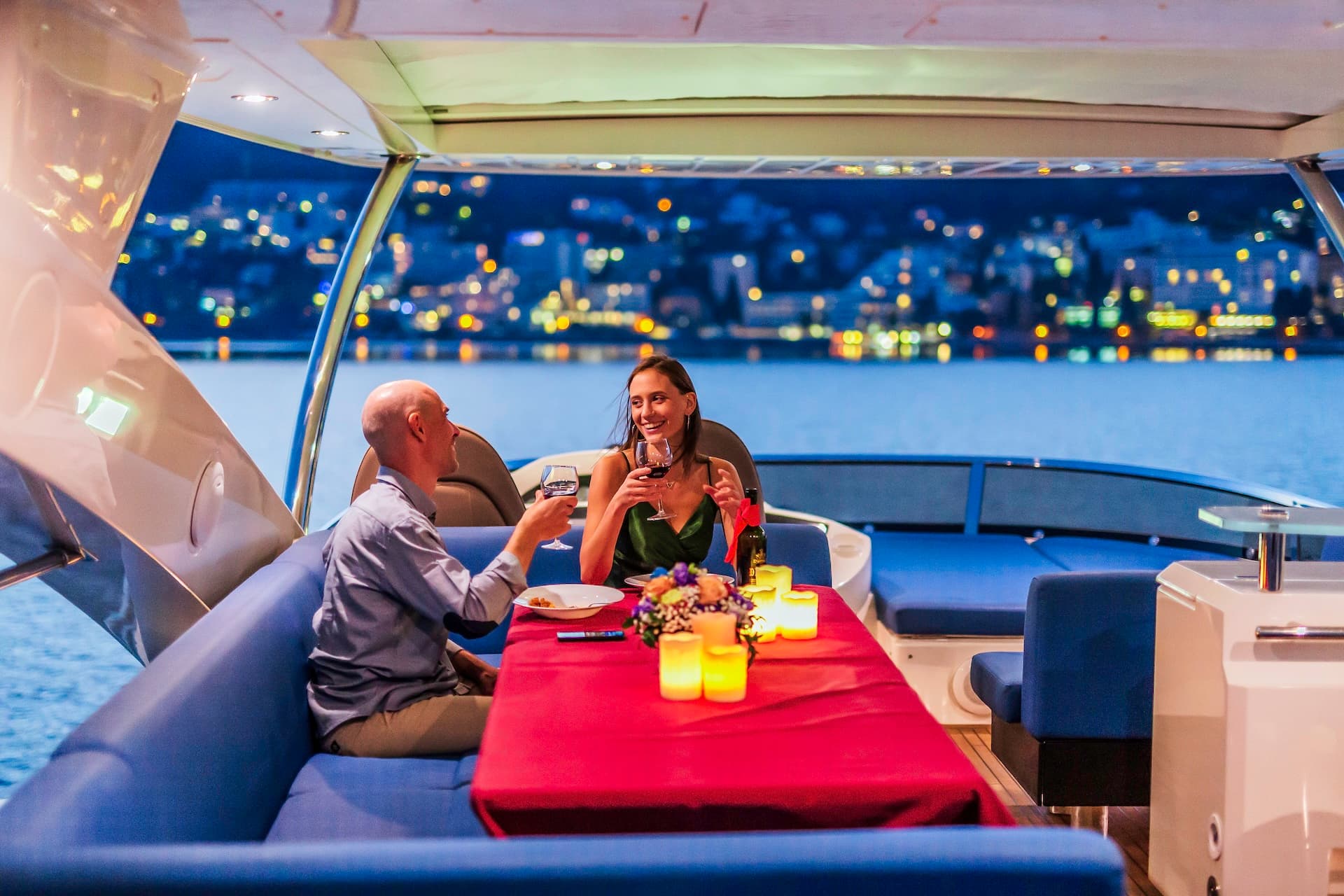 Couple enjoying romantic dinner with wine on yacht deck overlooking city lights in Croatia.
