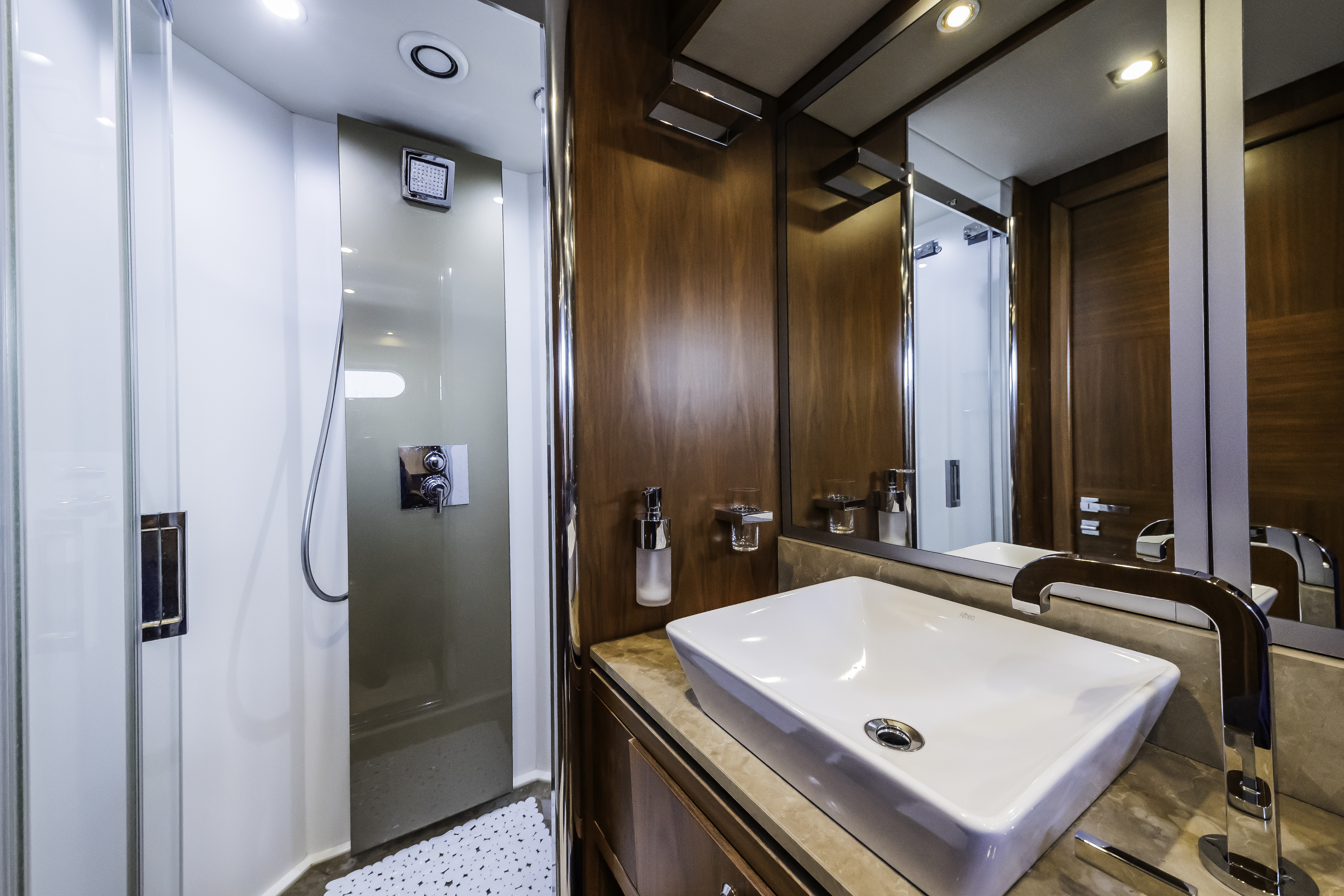 Luxury yacht bathroom with wood paneling, vessel sink, and glass shower stall.