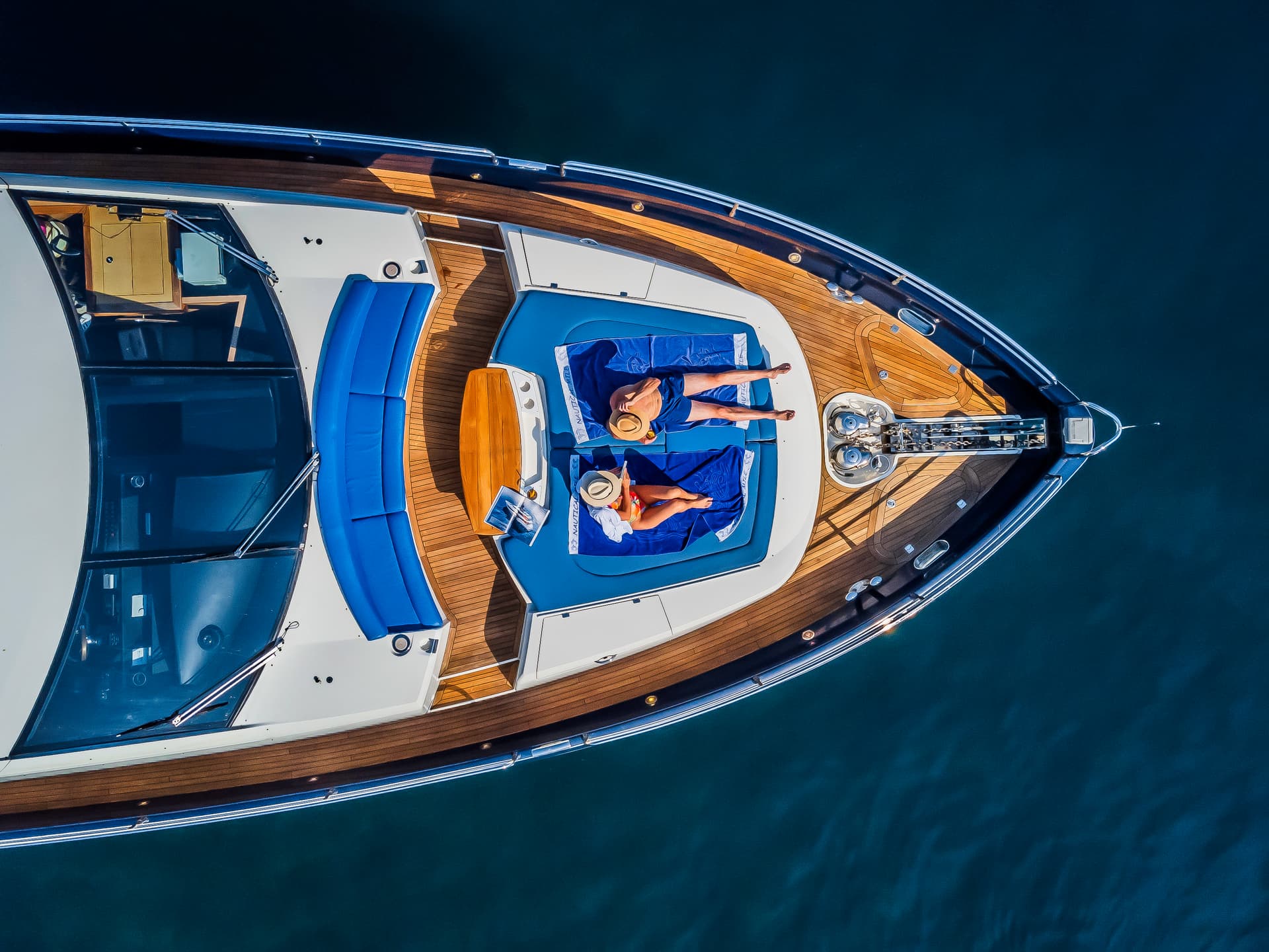 Yacht sunbathing area with two people on blue towels on dark blue water in Croatia.