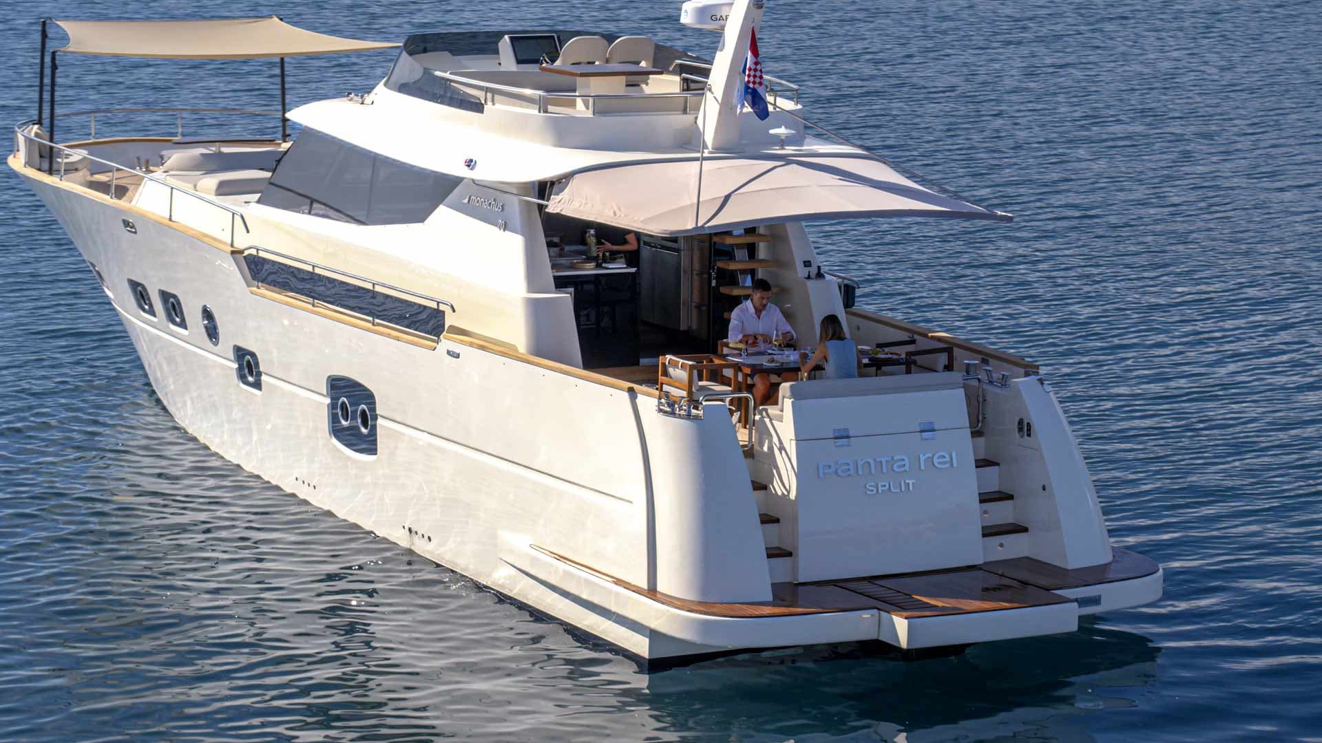 Motor yacht PANTA REI from Split on blue coastal waters with two people dining aft
