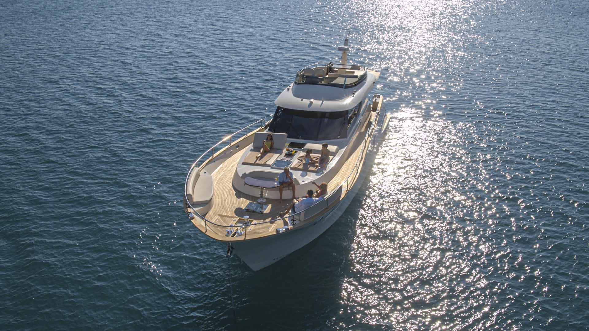 Motor yacht with people relaxing on the bow deck over sparkling blue water