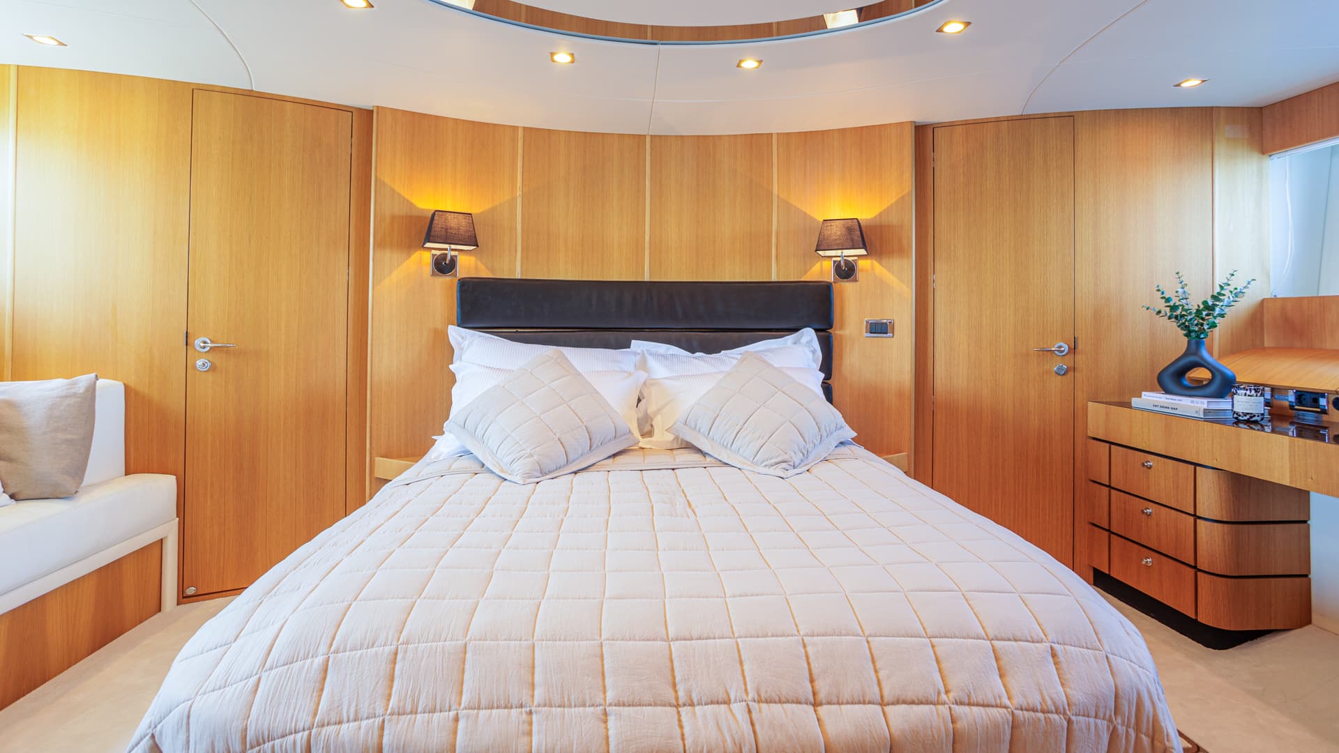 Master cabin interior with queen bed, wood paneling, and bedside lighting on a yacht.