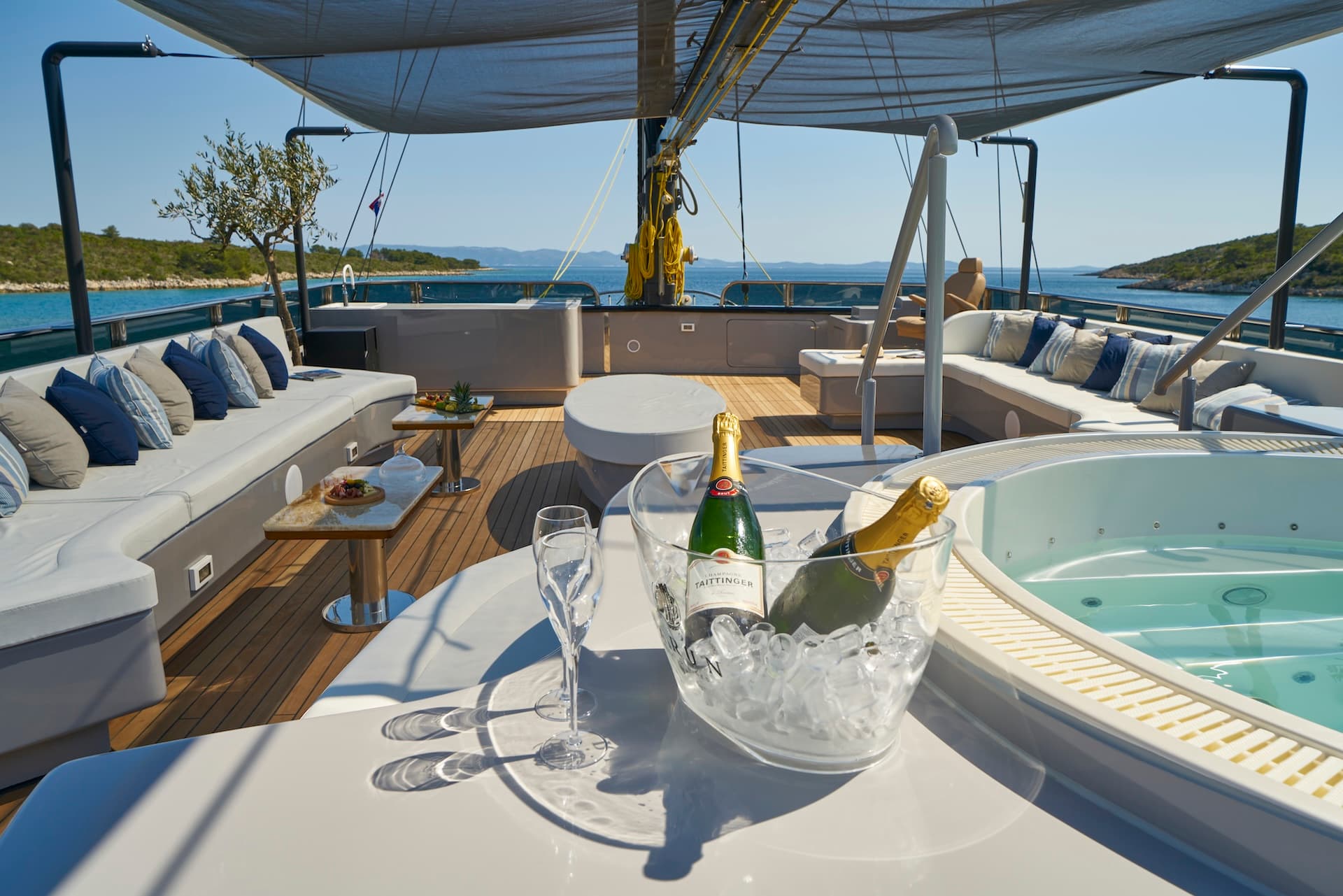 Yacht deck with champagne, hot tub, and island coastline view