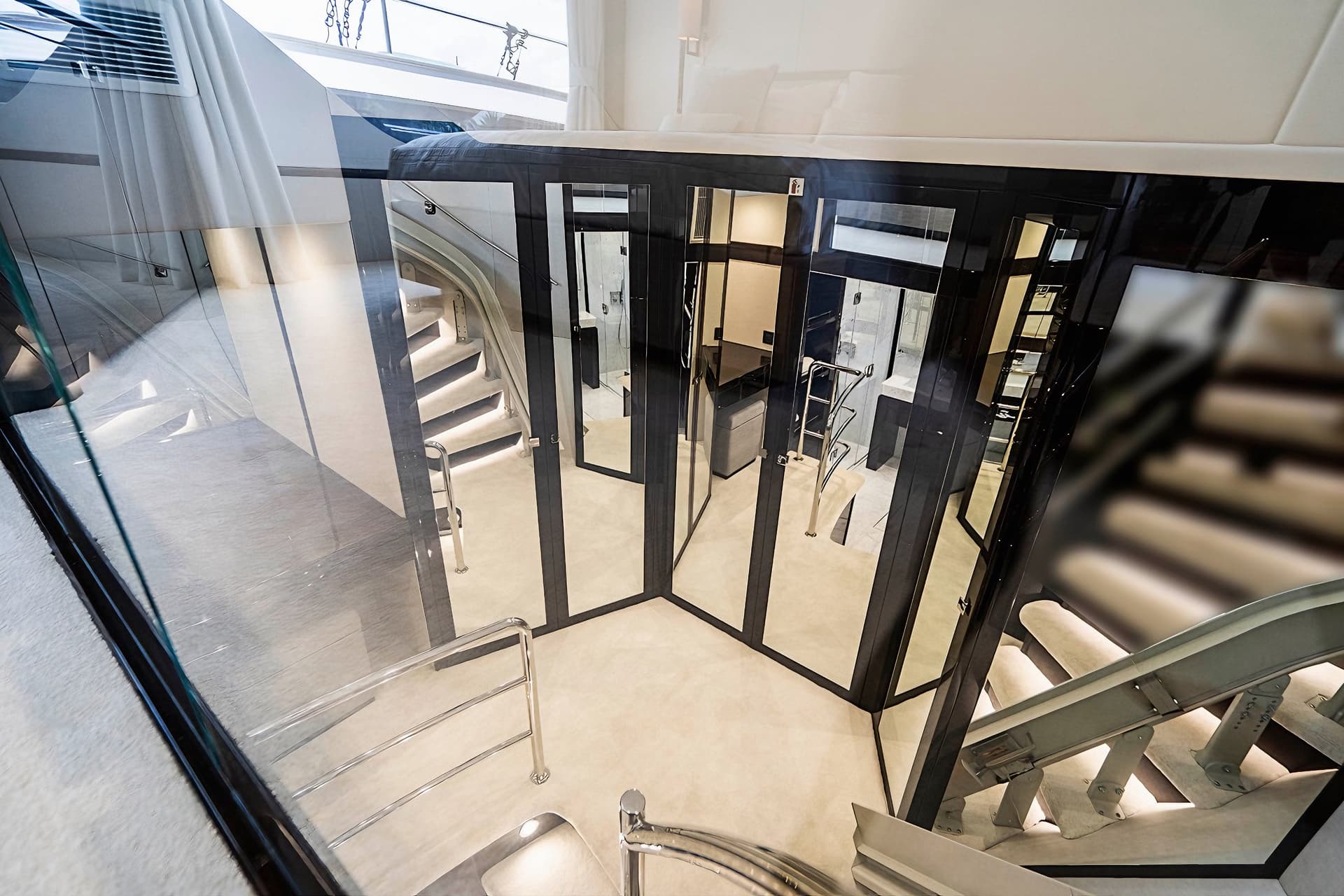 Interior view of a luxury yacht showing stairs, light flooring, and mirrored black cabinetry.