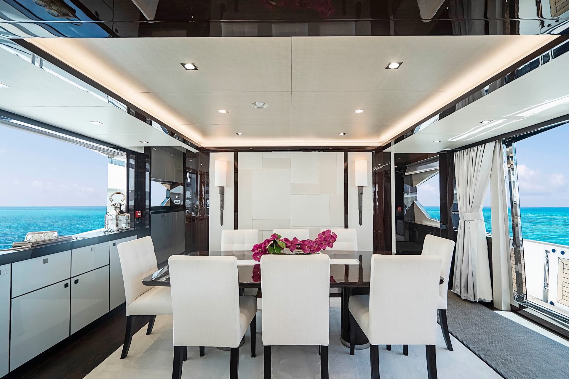 Luxury yacht dining area with white chairs overlooking turquoise ocean water.