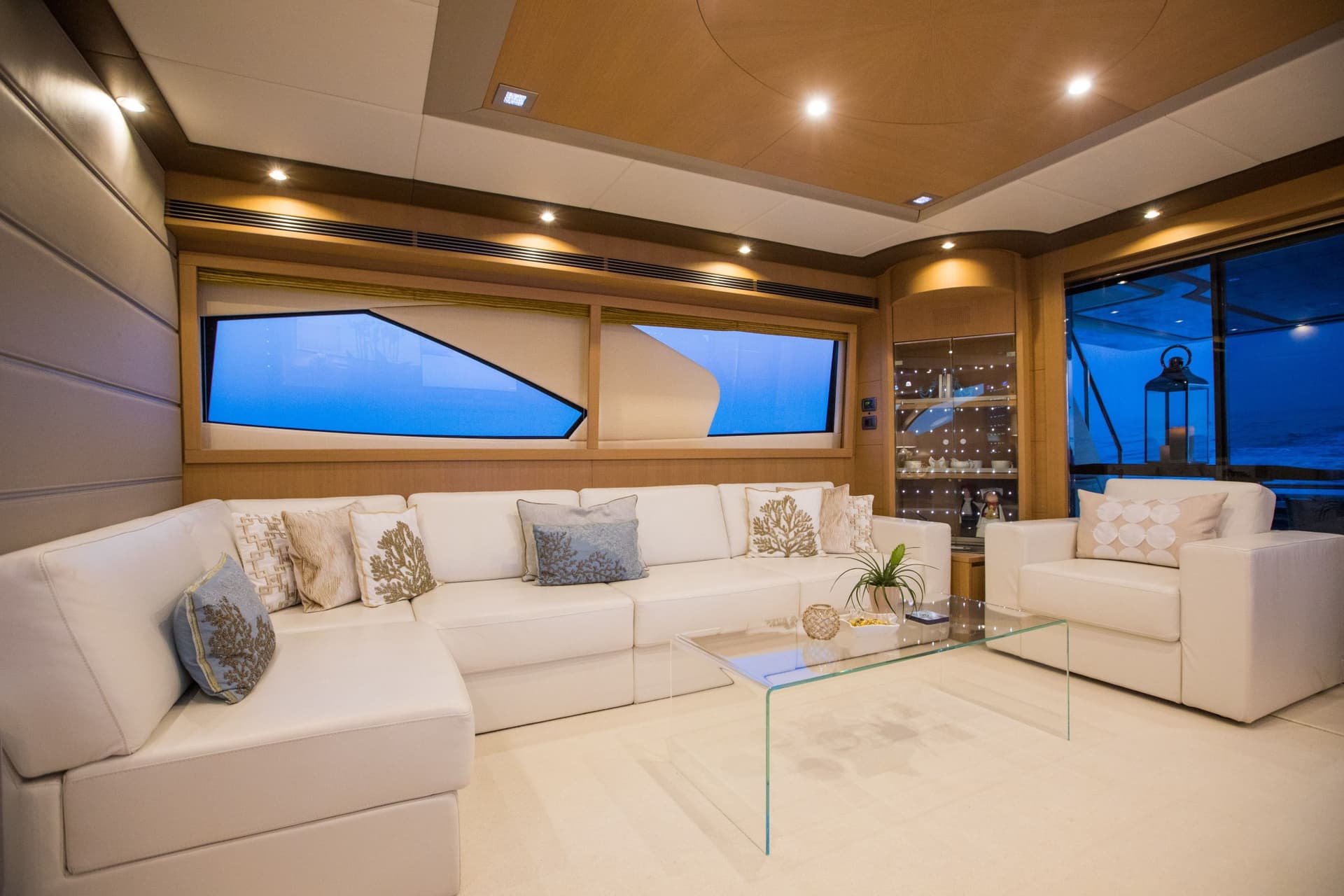Modern yacht interior lounge with white leather seating and blue ocean view at night