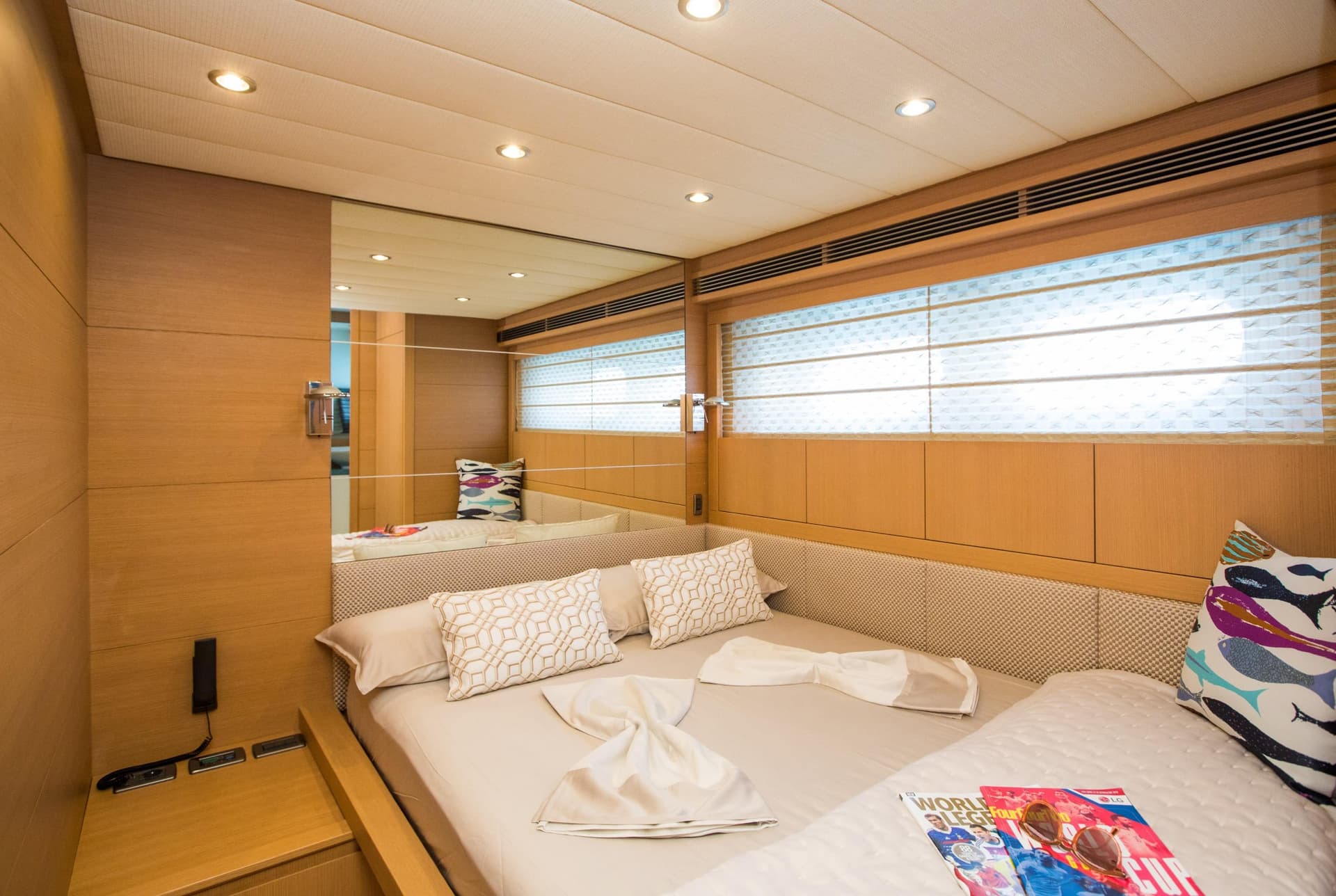 Double cabin interior with wood paneling, mirrored wall, and neatly made bed with decorative pillows.