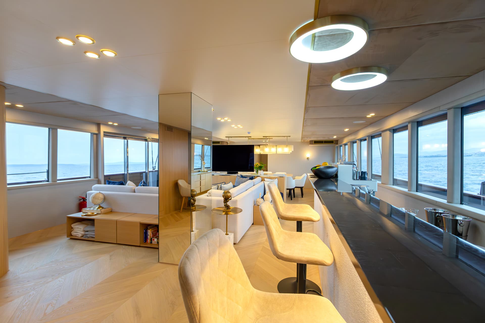 Modern yacht interior lounge with bar seating and sea view windows.