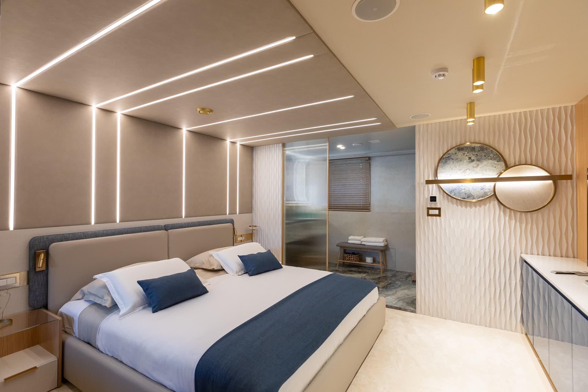 Modern yacht master cabin with illuminated headboard and blue bedding in neutral tones