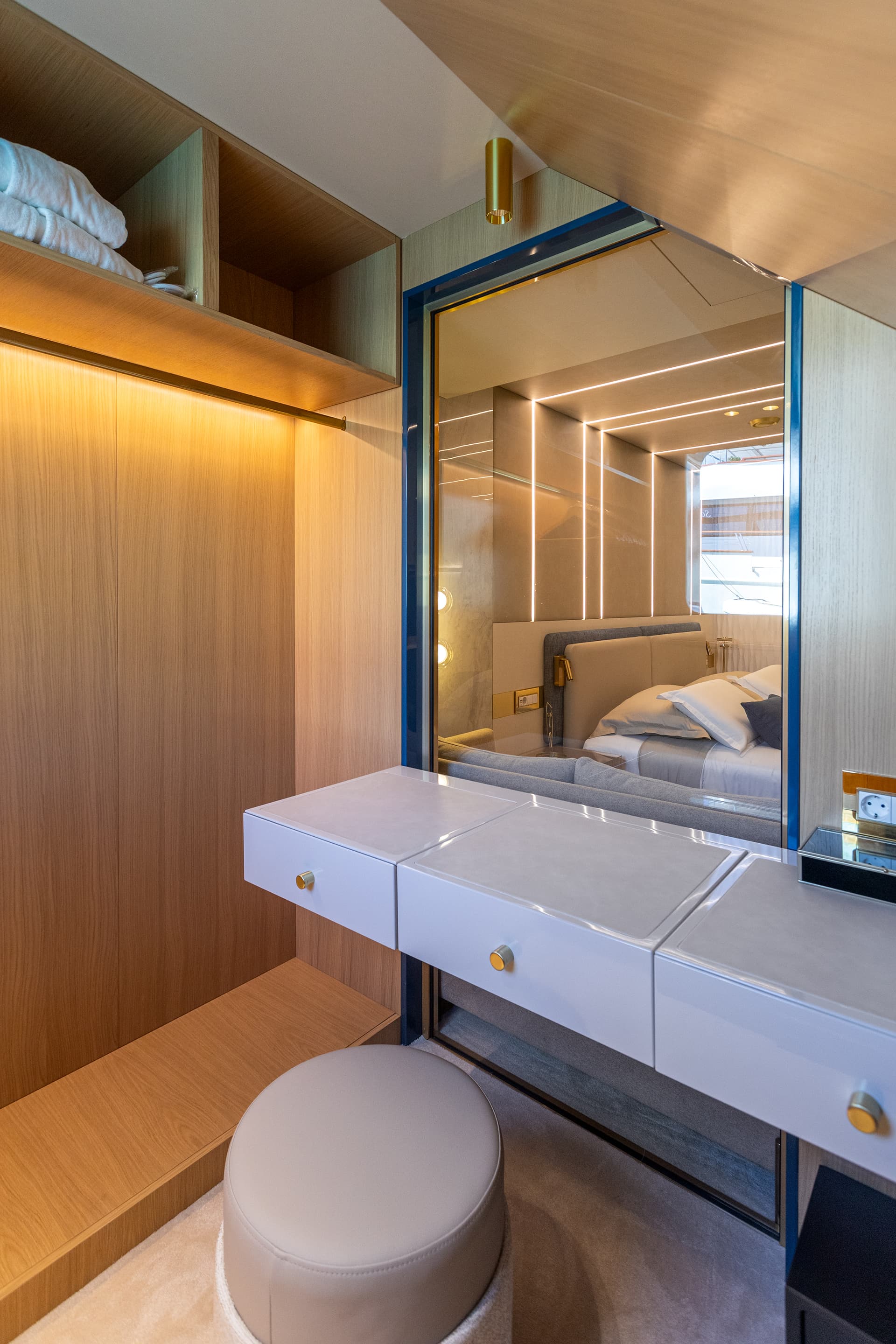 Vanity area with white drawers, wood paneling, and mirror reflecting a modern cabin interior.