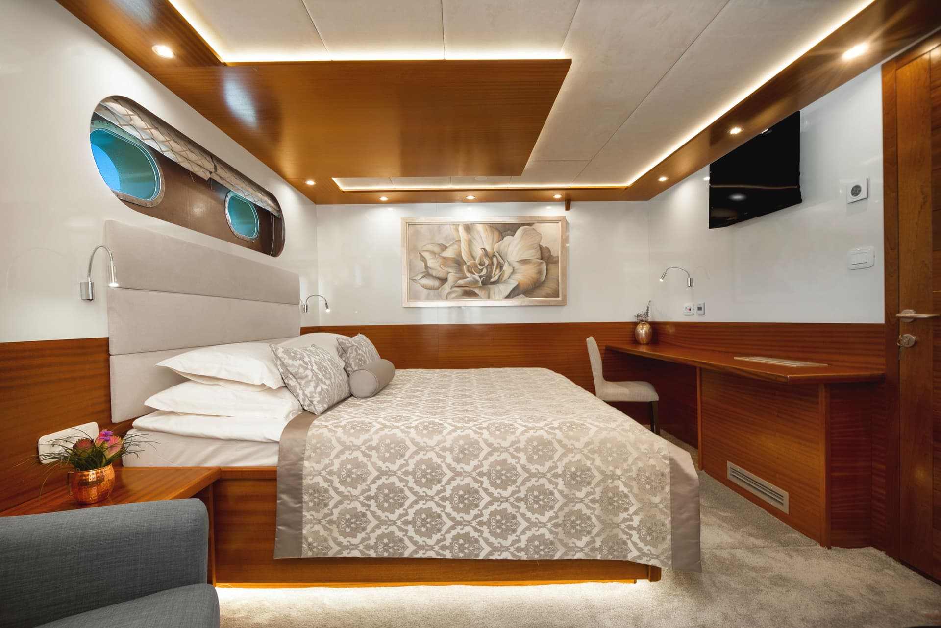 Luxurious yacht cabin bedroom with porthole windows, wood paneling, and patterned bedding