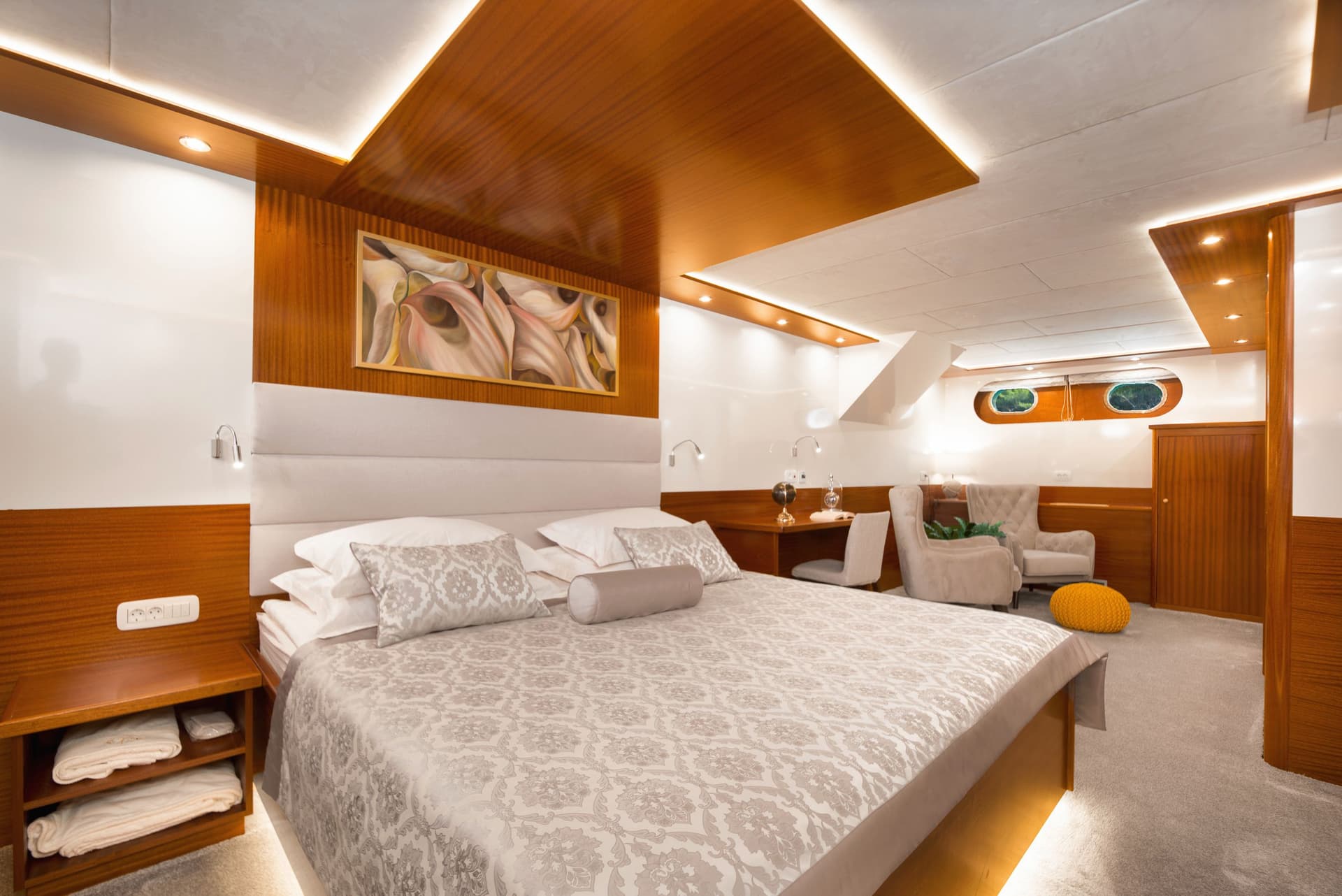 Master cabin interior with wood paneling, plush bedding, and porthole windows suggesting a boat.