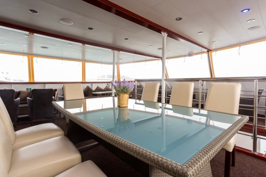 Dining area with glass table and cream chairs inside a boat or ship cabin