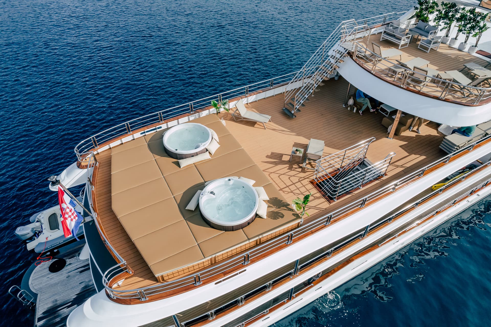 Luxury yacht deck with two hot tubs and Croatian flag on deep blue sea