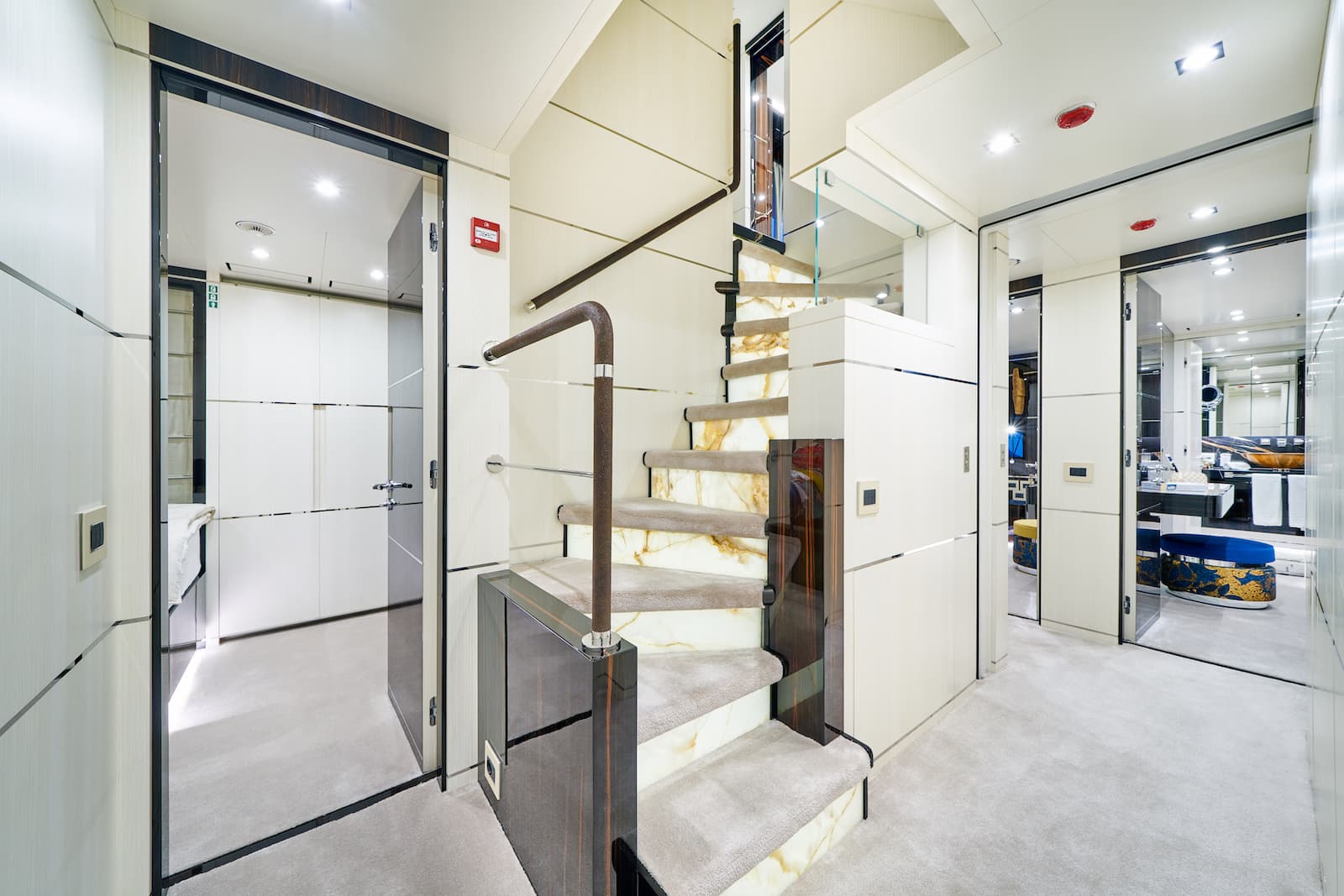 Luxurious yacht interior with marble staircase, light wood paneling, and plush carpet.
