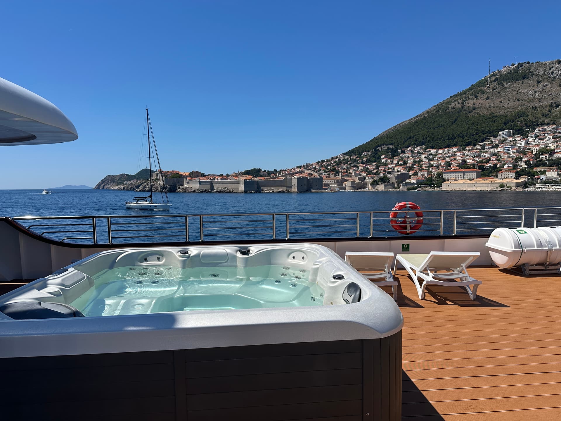 Hot tub on yacht sundeck overlooking coastal town and sea