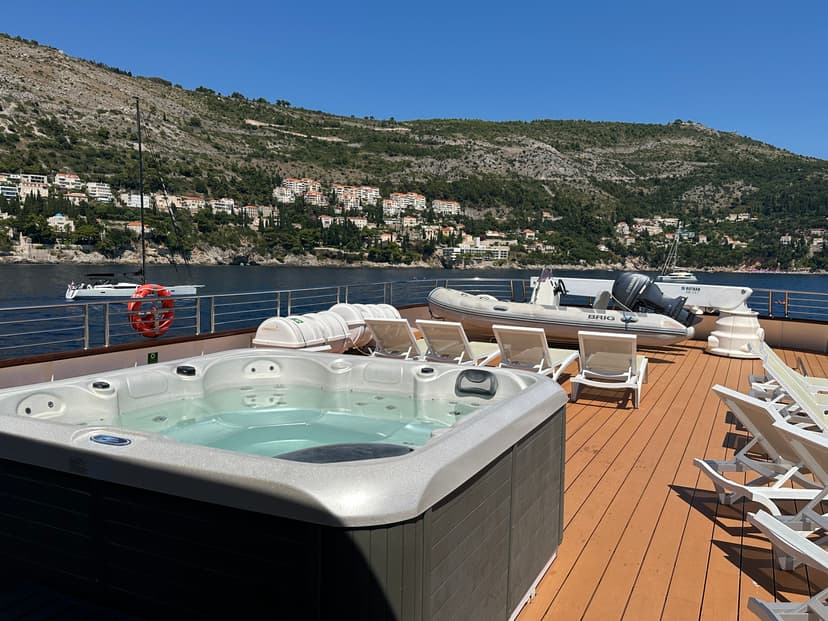 Wooden sundeck on yacht with hot tub and lounge chairs overlooking coastal town