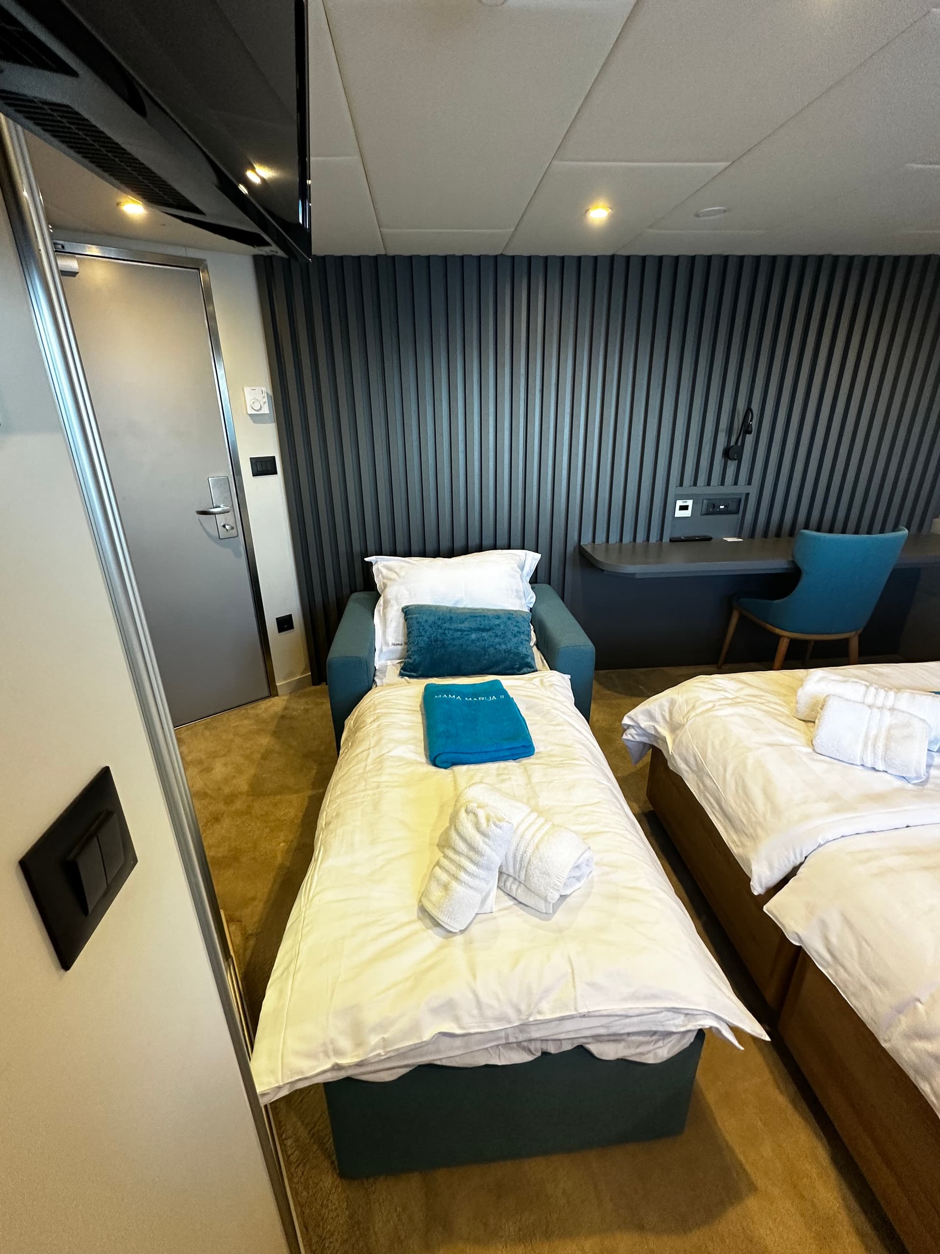 Hotel room with triple beds, white linens, and blue accent pillows
