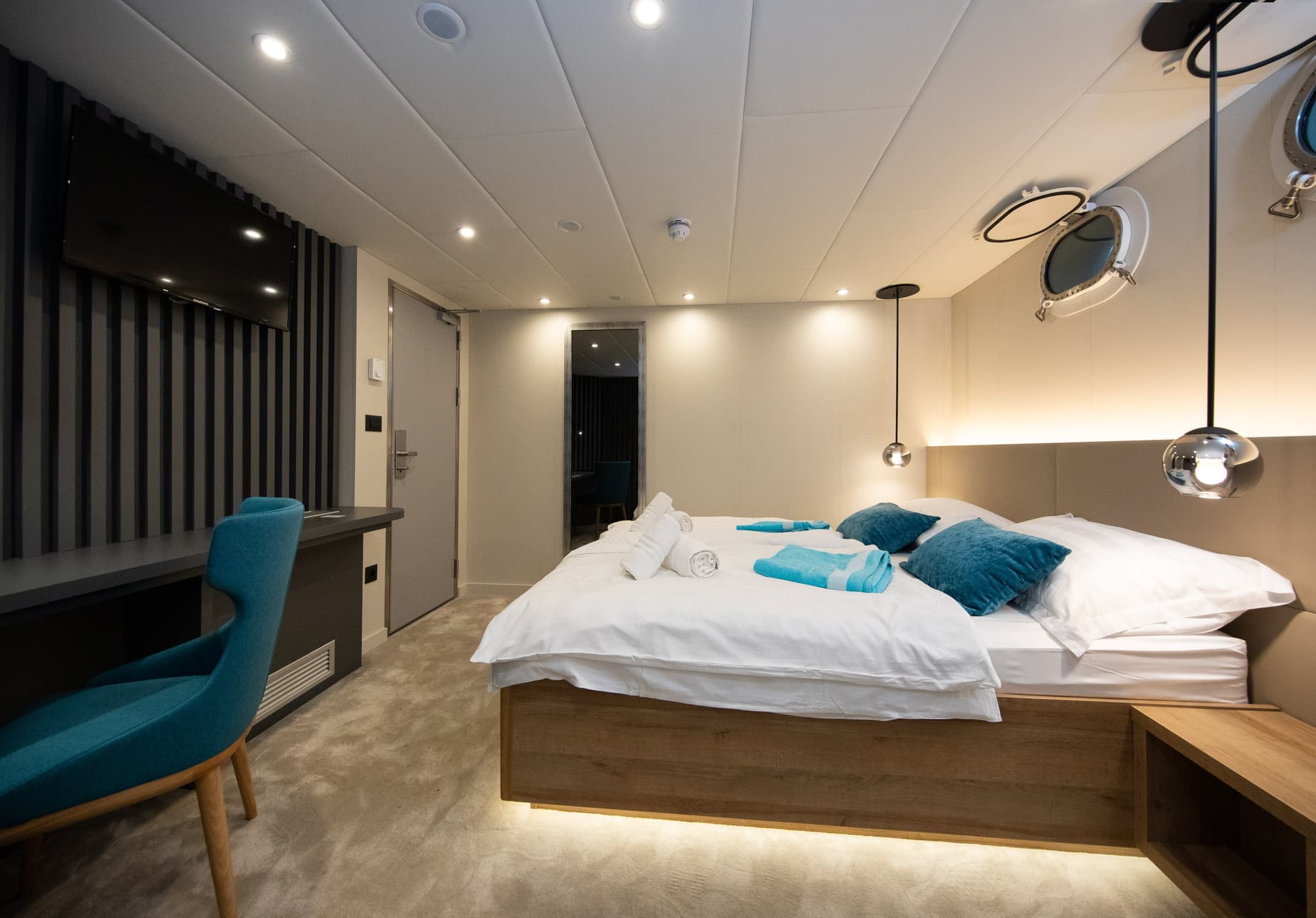 Modern cruise ship standard cabin with twin beds and porthole window