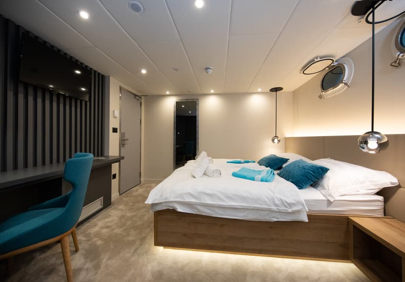 Modern cruise ship standard cabin with twin beds and porthole window