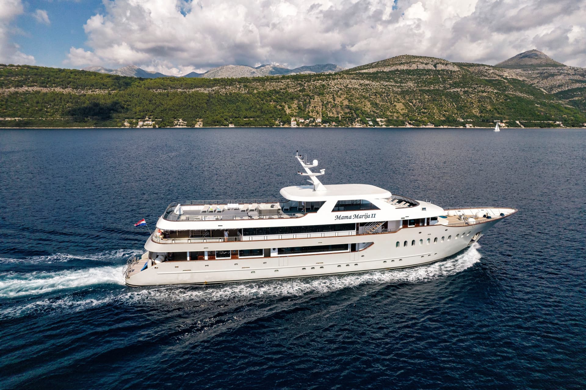 Mama Marija II yacht cruising on coastal waters with mountains in the background