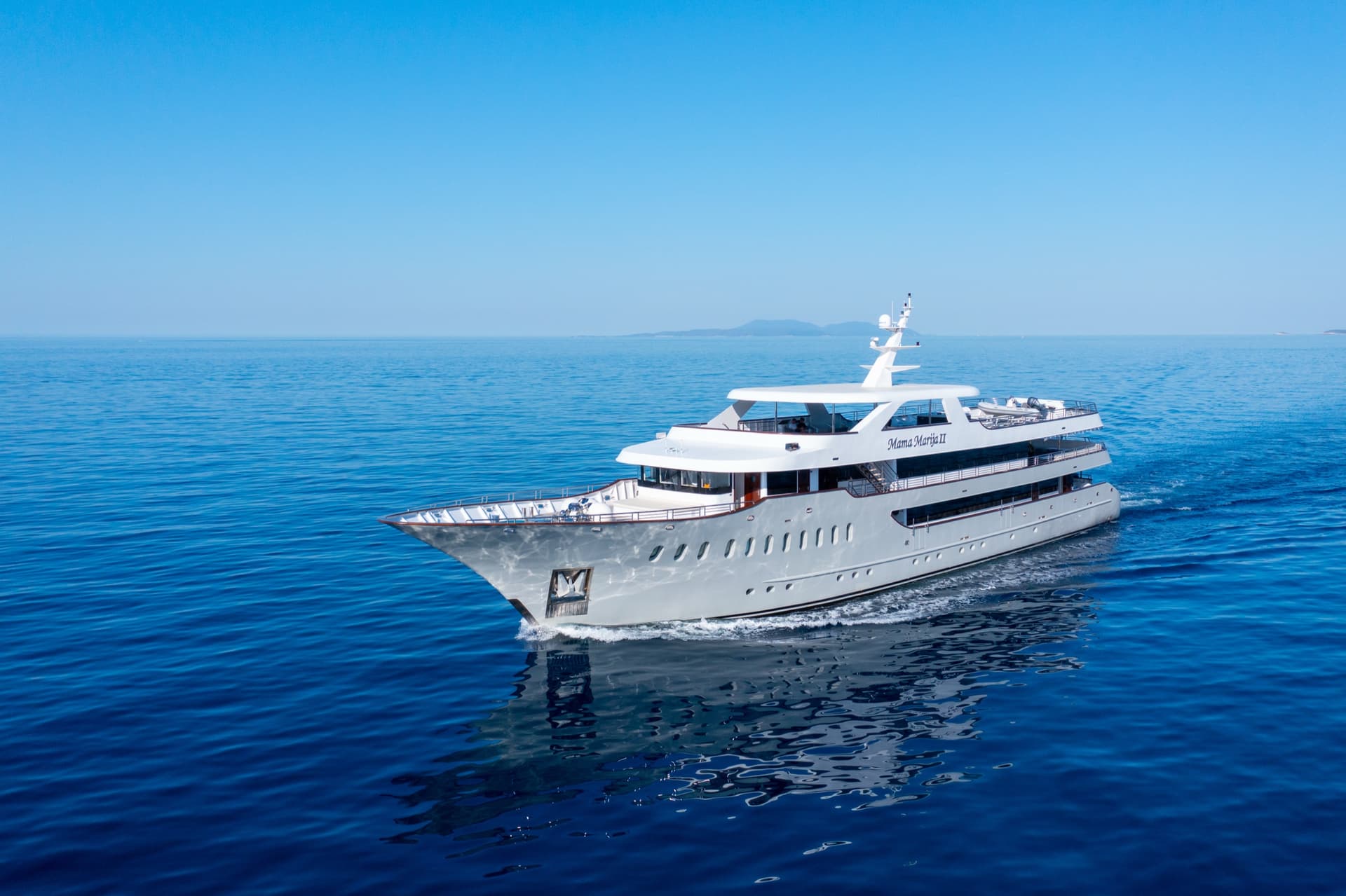 White yacht cruising on calm blue sea under clear sky