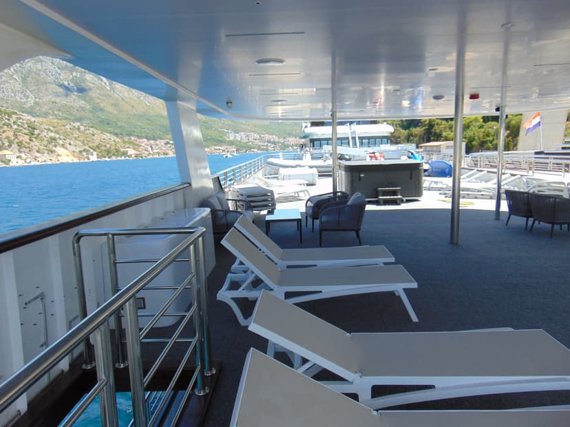 Yacht deck with lounge chairs and hot tub overlooking coastal mountains
