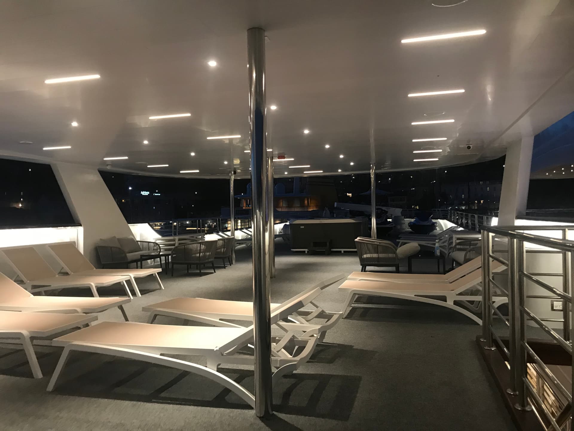 Yacht sun deck with lounge chairs and illuminated ceiling at night