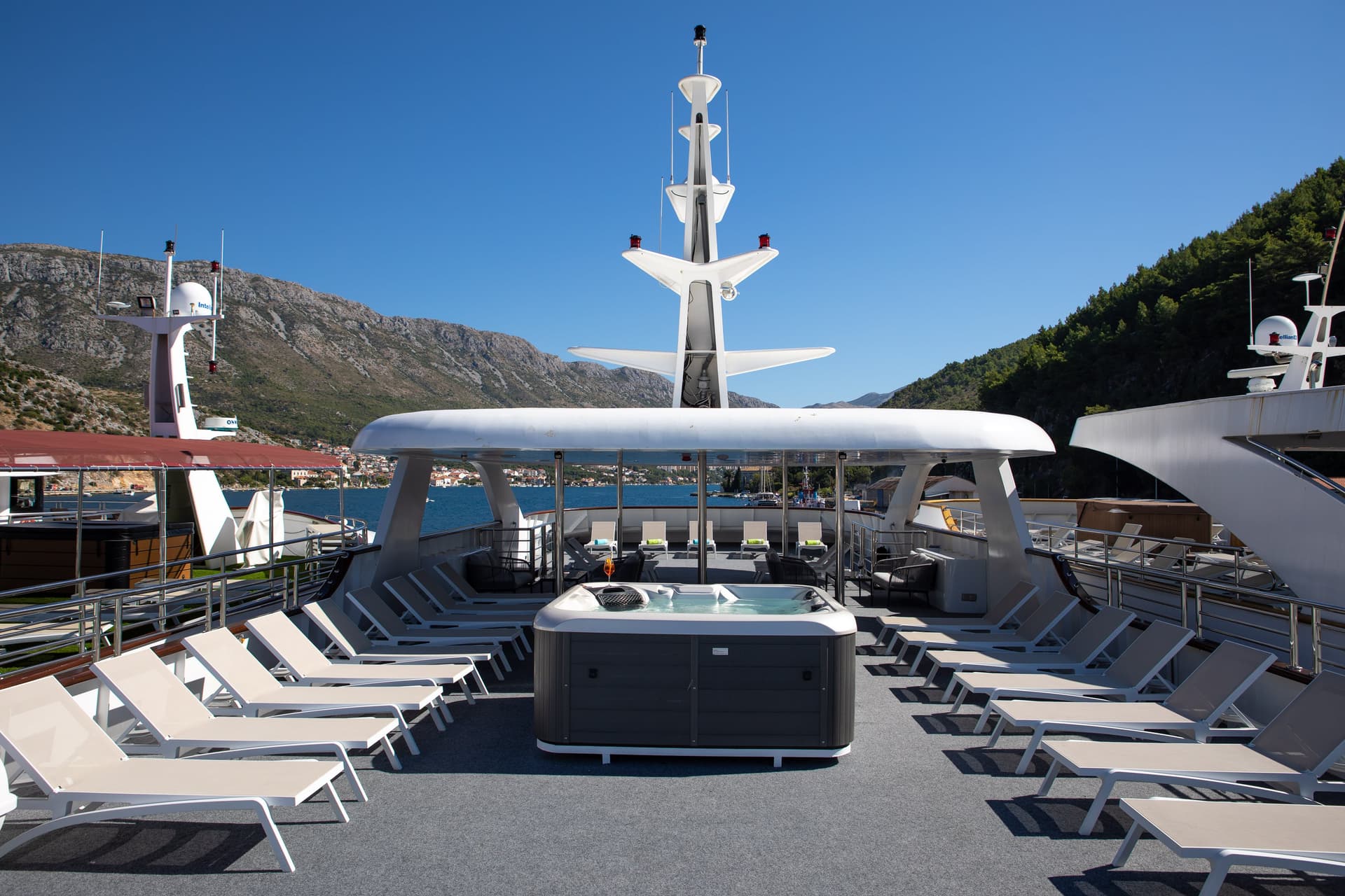 Yacht sun deck with hot tub and lounge chairs overlooking coastal mountains