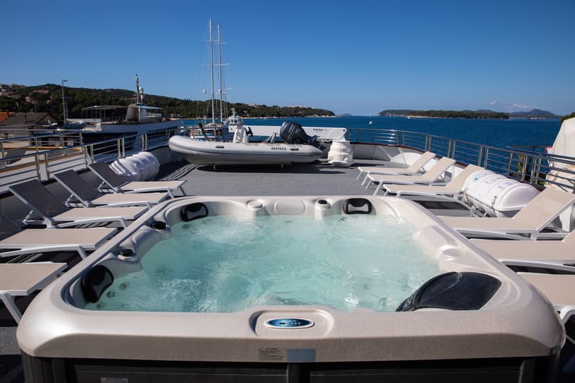 Hot tub and lounge chairs on sunny yacht deck overlooking sea and islands