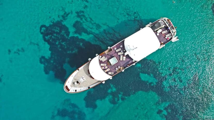 Yacht on turquoise coastal waters from above