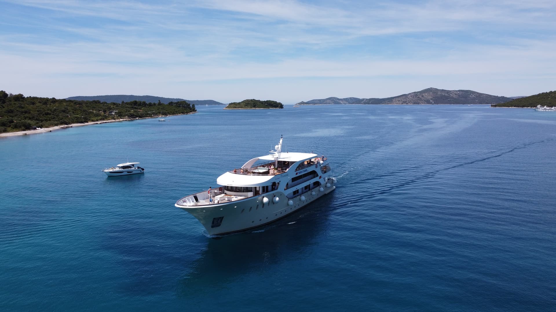 Large white cruise ship sailing on blue coastal waters with small islands